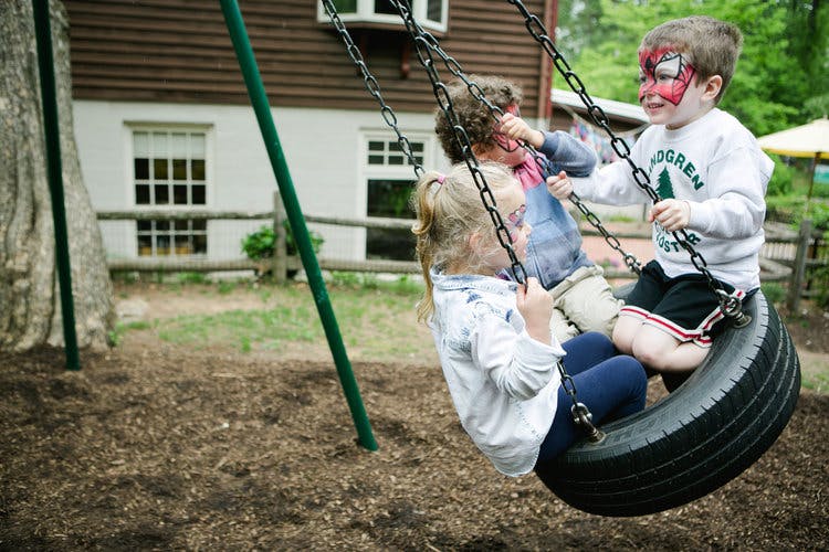Three children playing on a tire swing