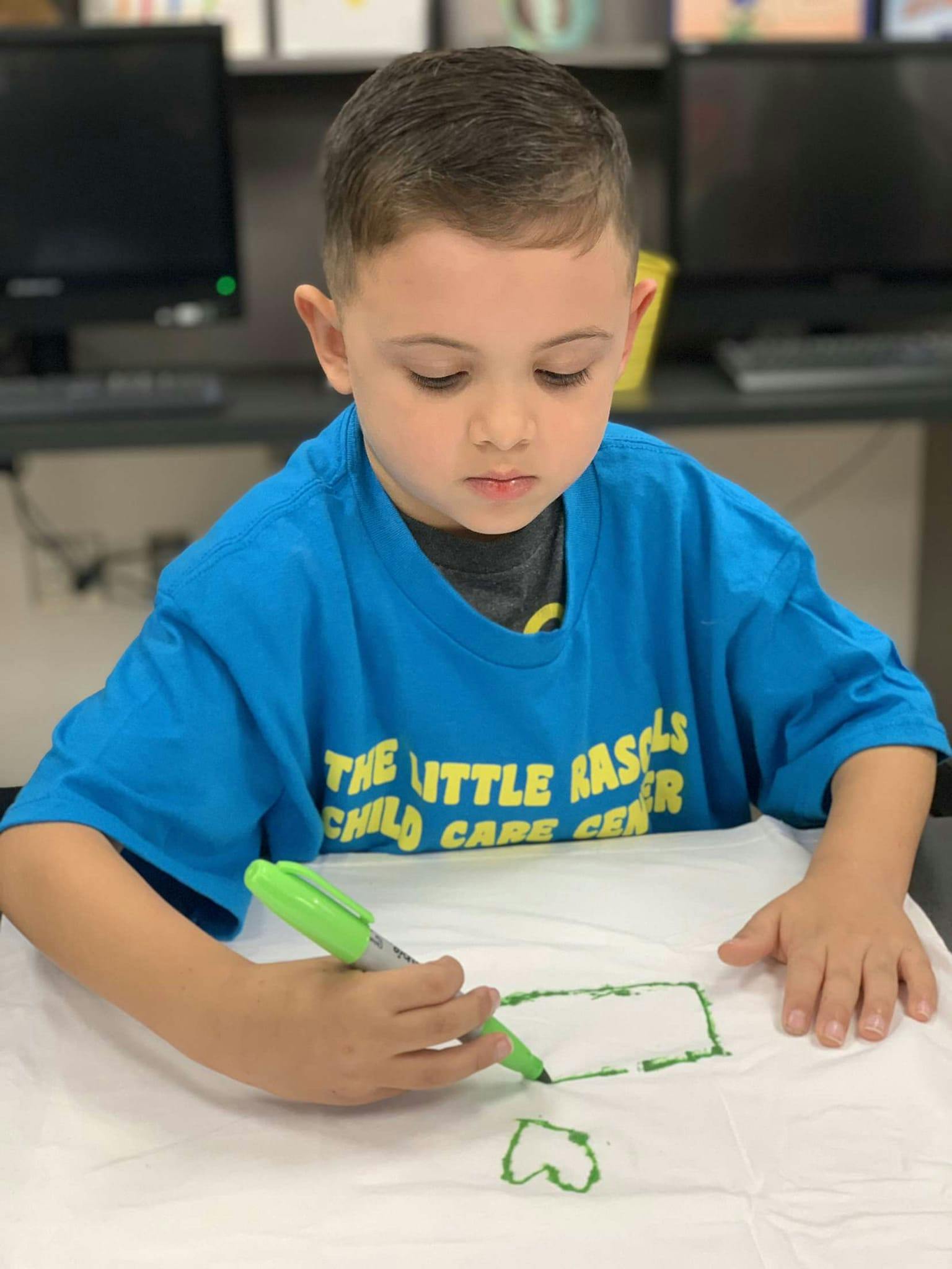 Child drawing on paper with a green marker