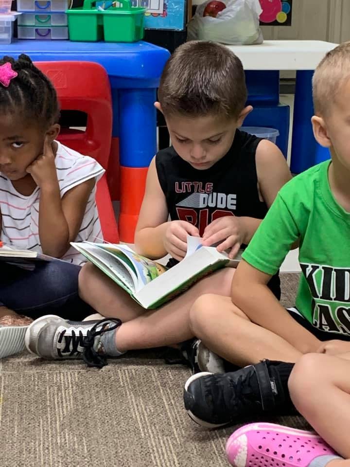 Three children sitting on the floor reading books