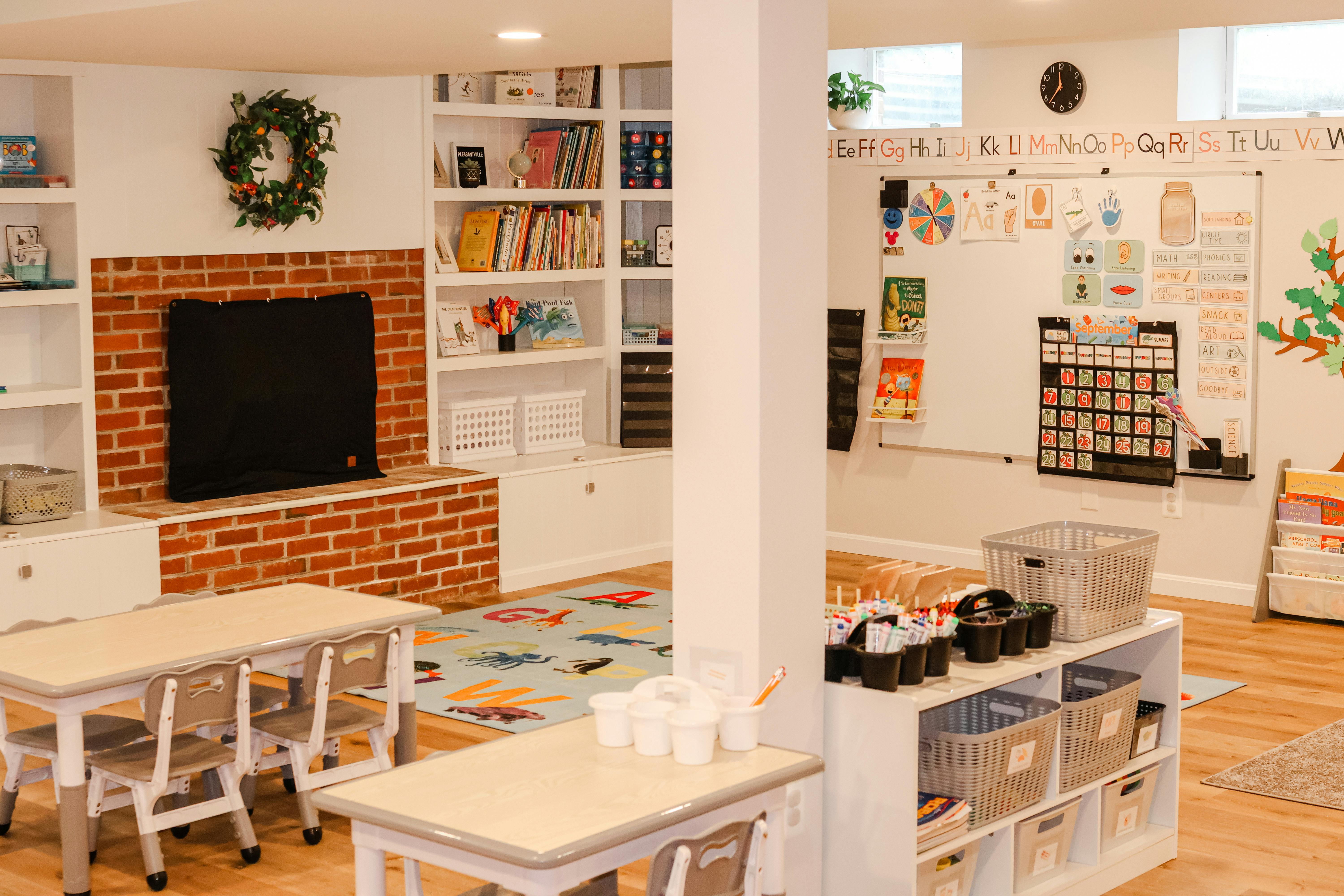 Classroom with small tables and chairs, shelves, and a whiteboard