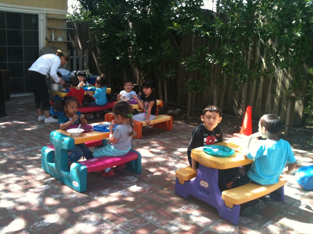 Children sitting at small tables outdoors