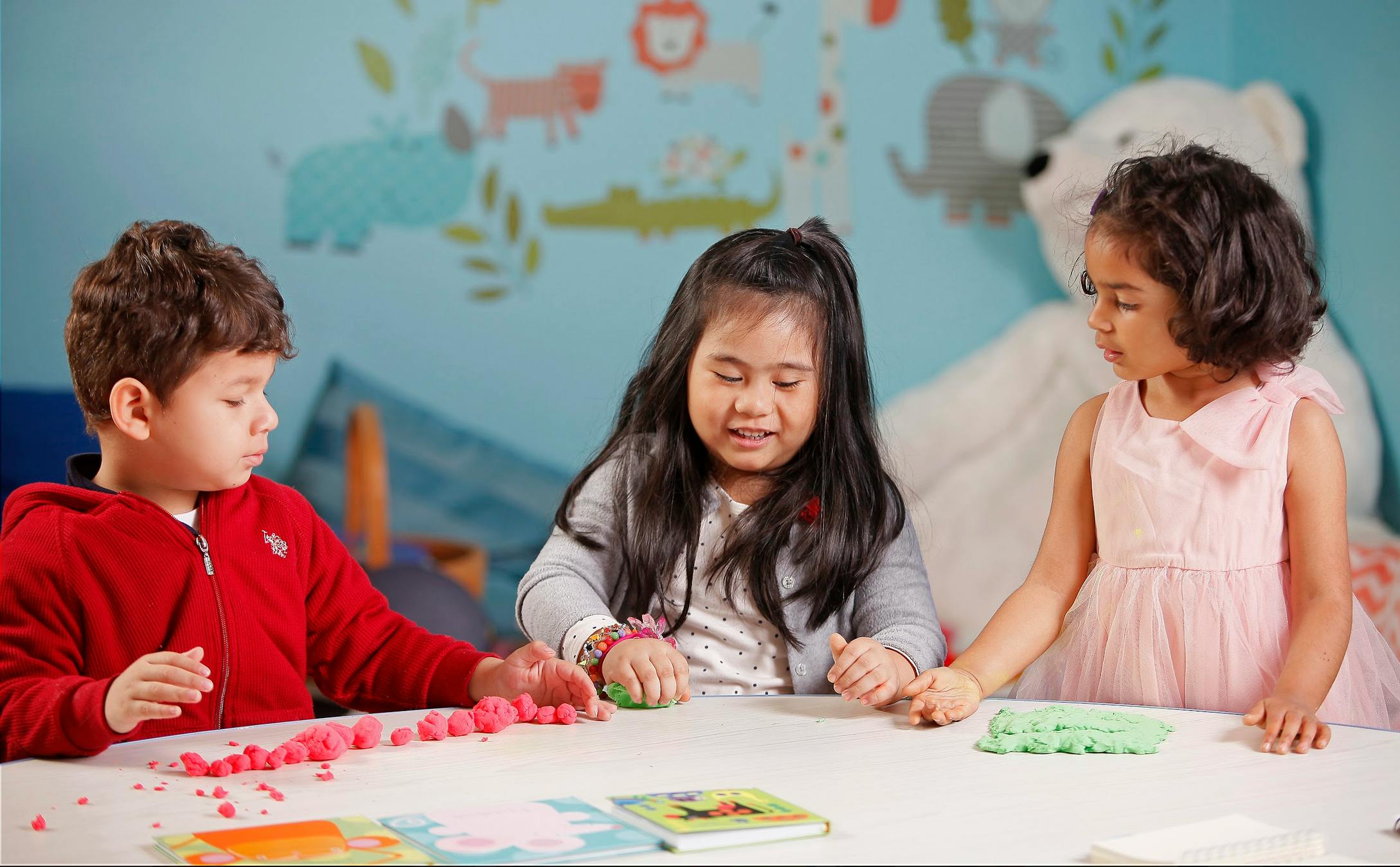 Three children playing with modeling clay at a table