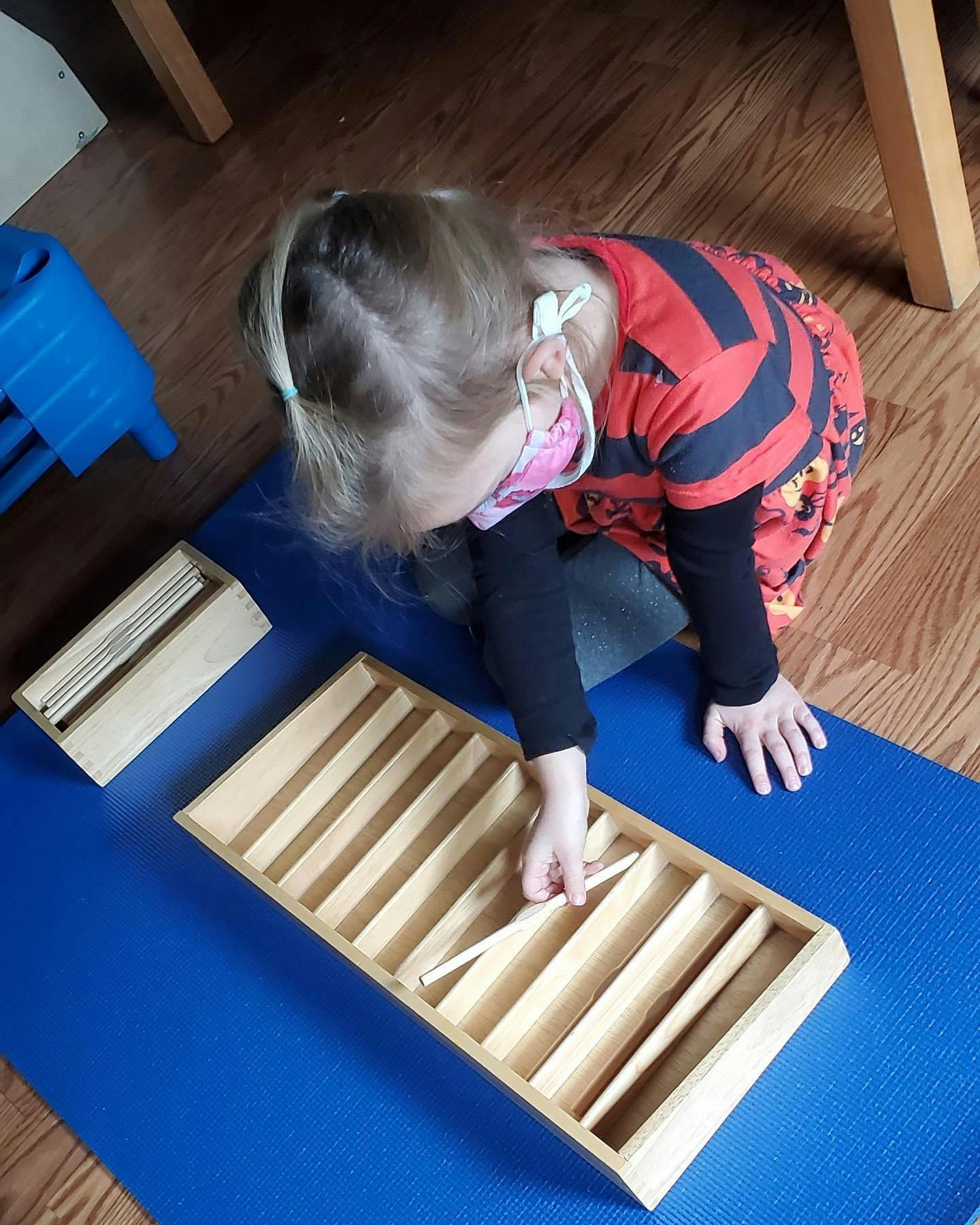 Child playing with wooden sorting toy on a blue mat