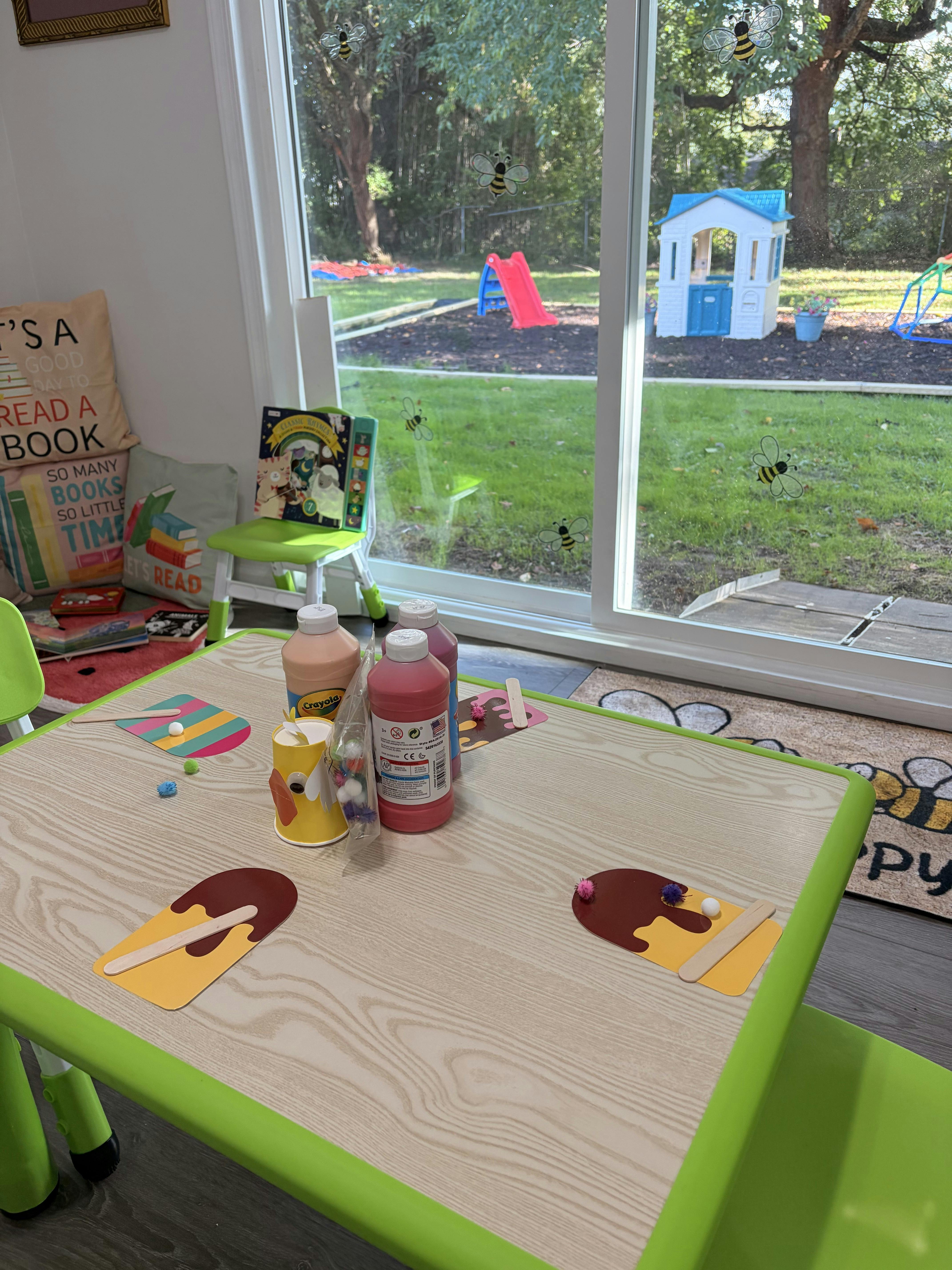Craft table with paint bottles and paper popsicle cutouts in a playroom