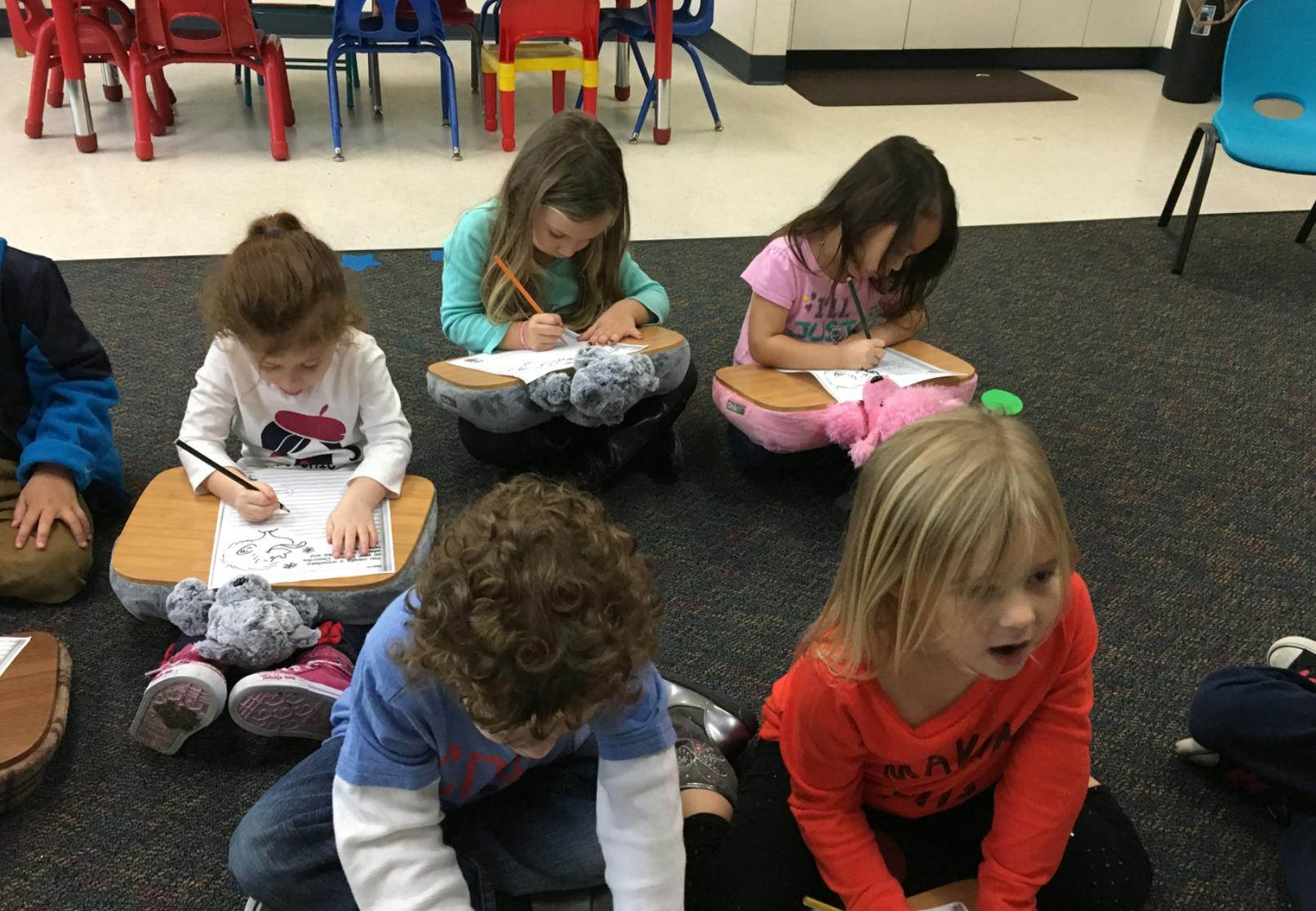 Children sitting on the floor drawing and writing