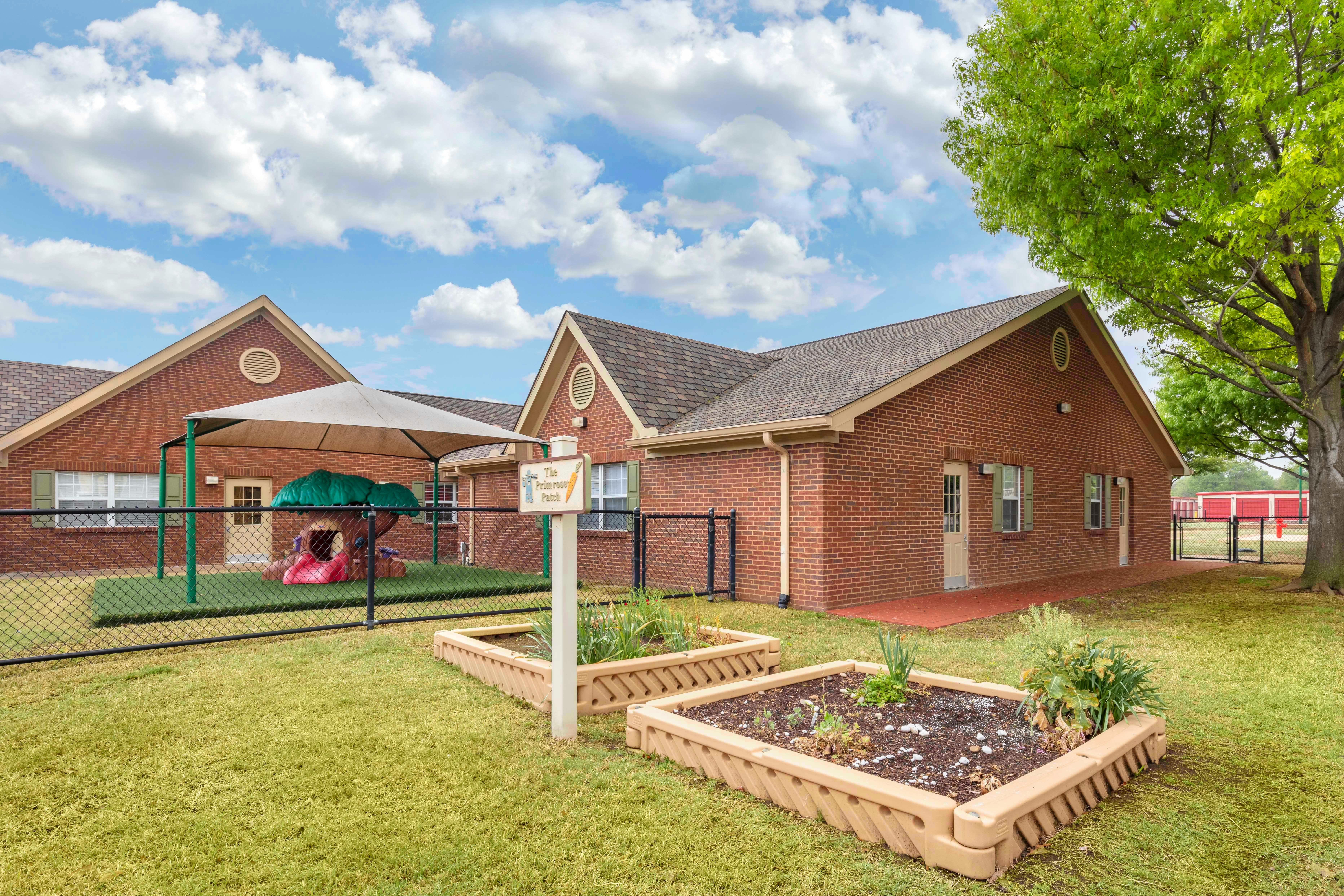 Brick building with a playground and raised garden beds in the foreground