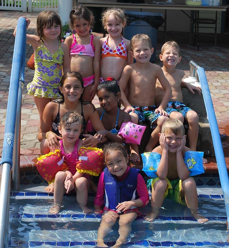 Group of children and teens sitting on pool steps