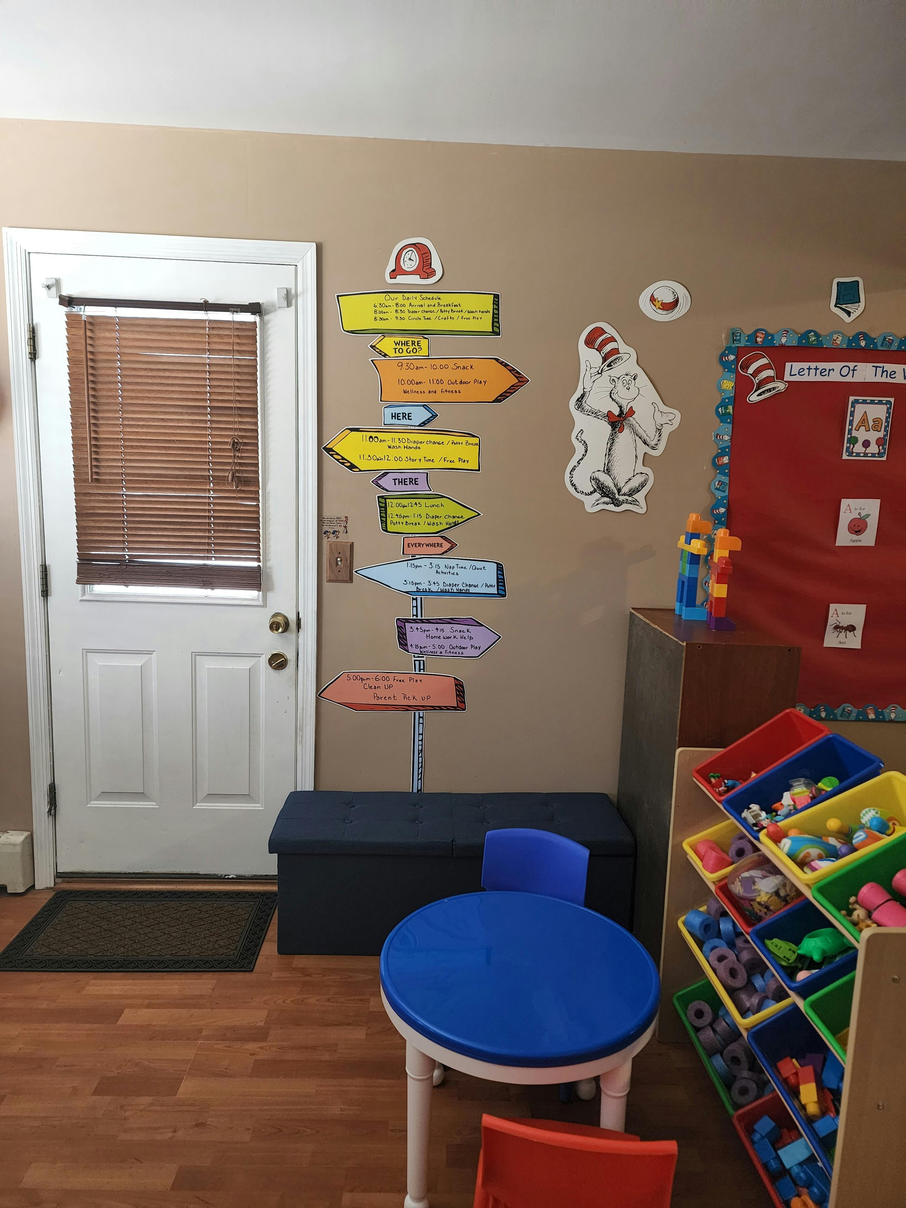 Classroom with a white door, colorful directional signs, and a small blue table