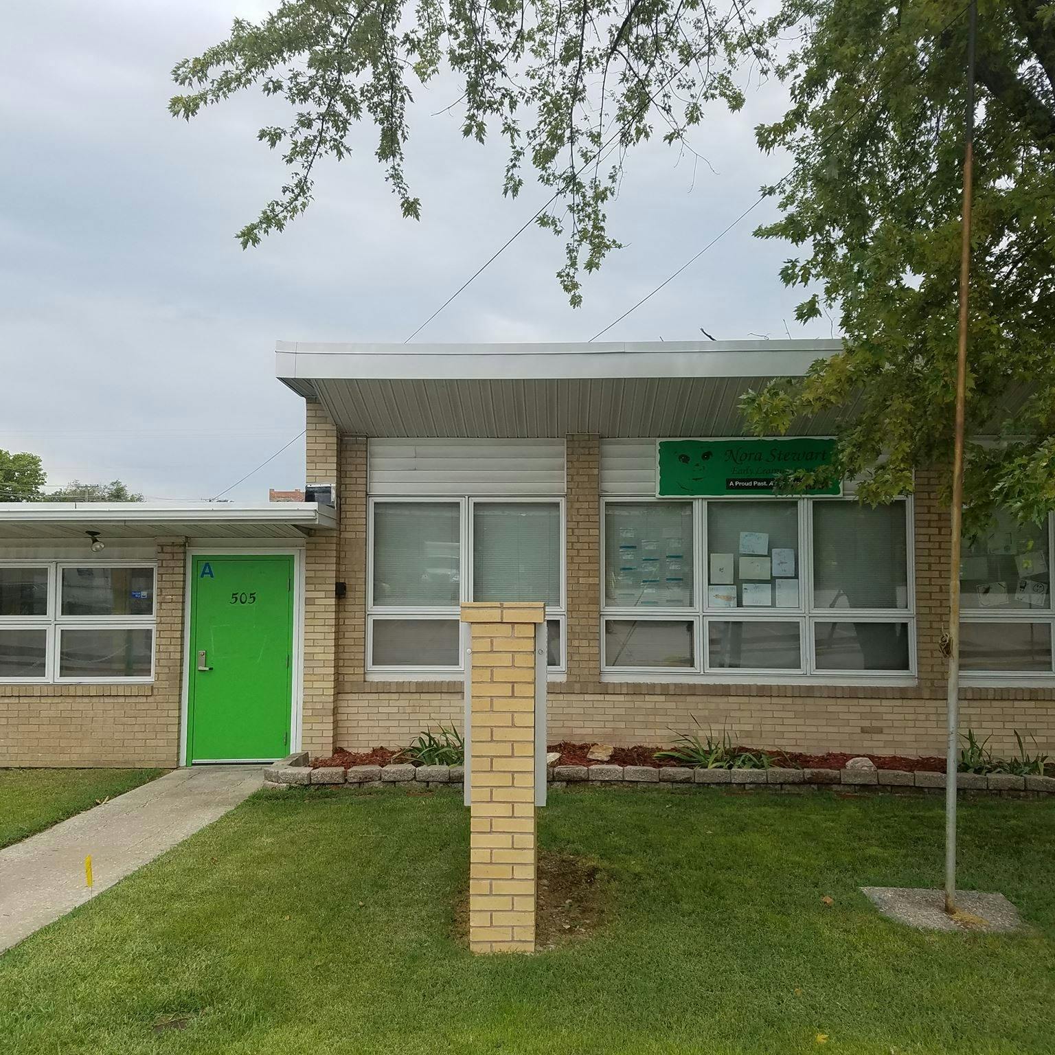 Brick building with a bright green door and multiple windows