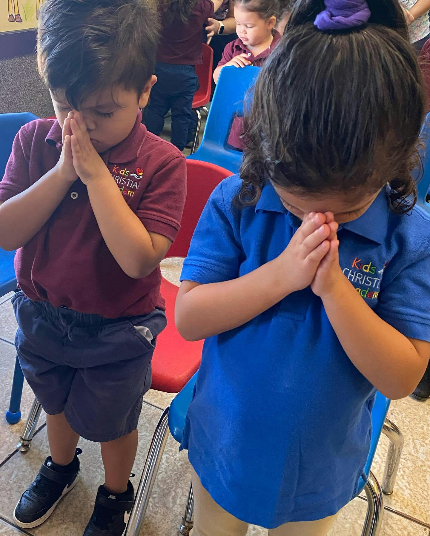 Two children in polo shirts with hands clasped as if in prayer