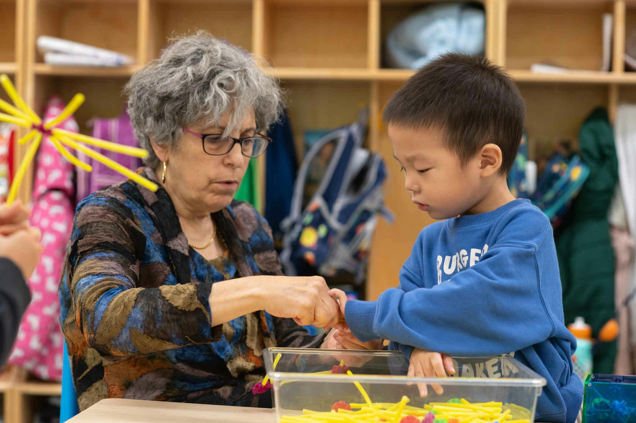 Adult and child playing with small objects in a container