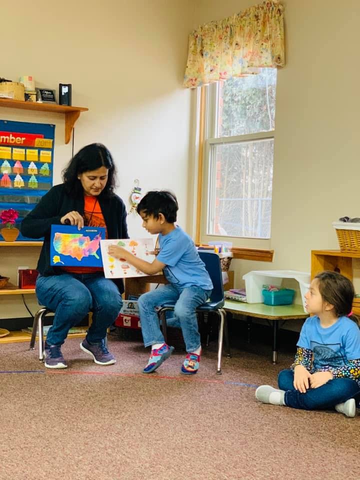 Person showing a child a map while another child watches