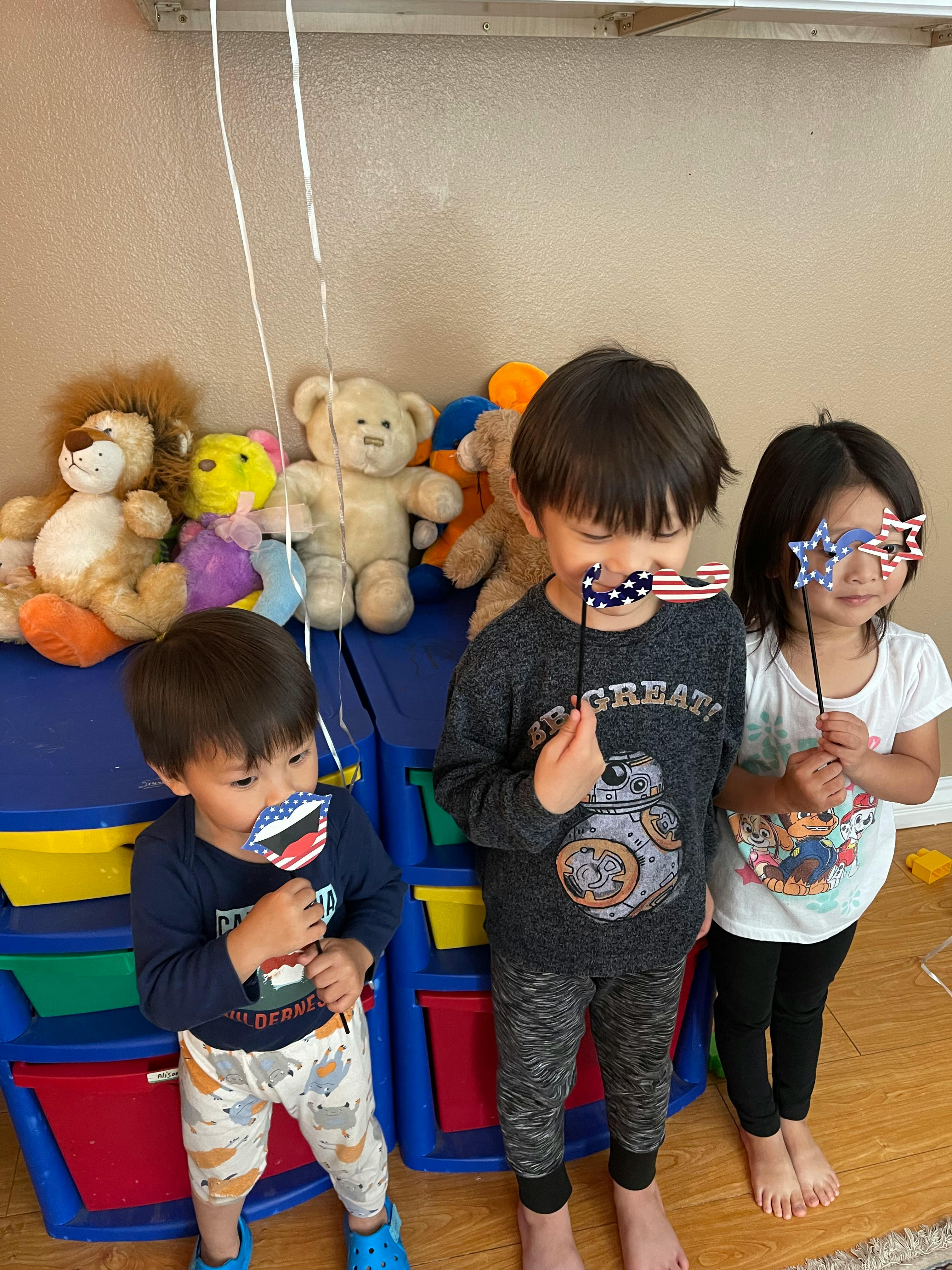 Three children holding up patriotic-themed photo booth props
