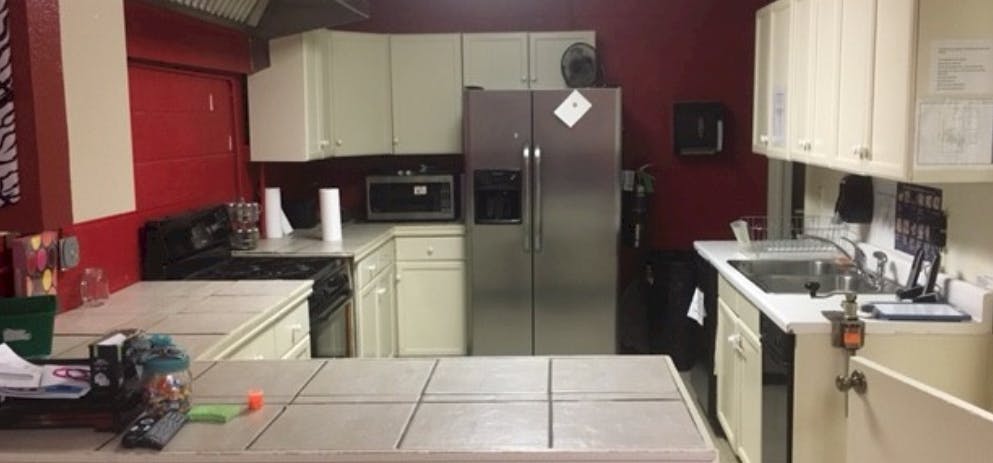 Kitchen with white cabinets, stainless steel refrigerator, and red walls
