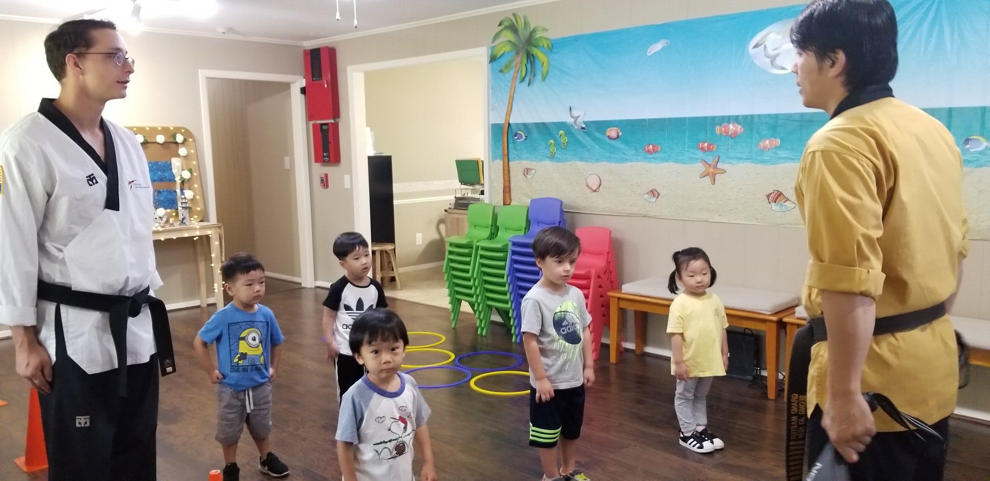 Two people in martial arts uniforms instructing children