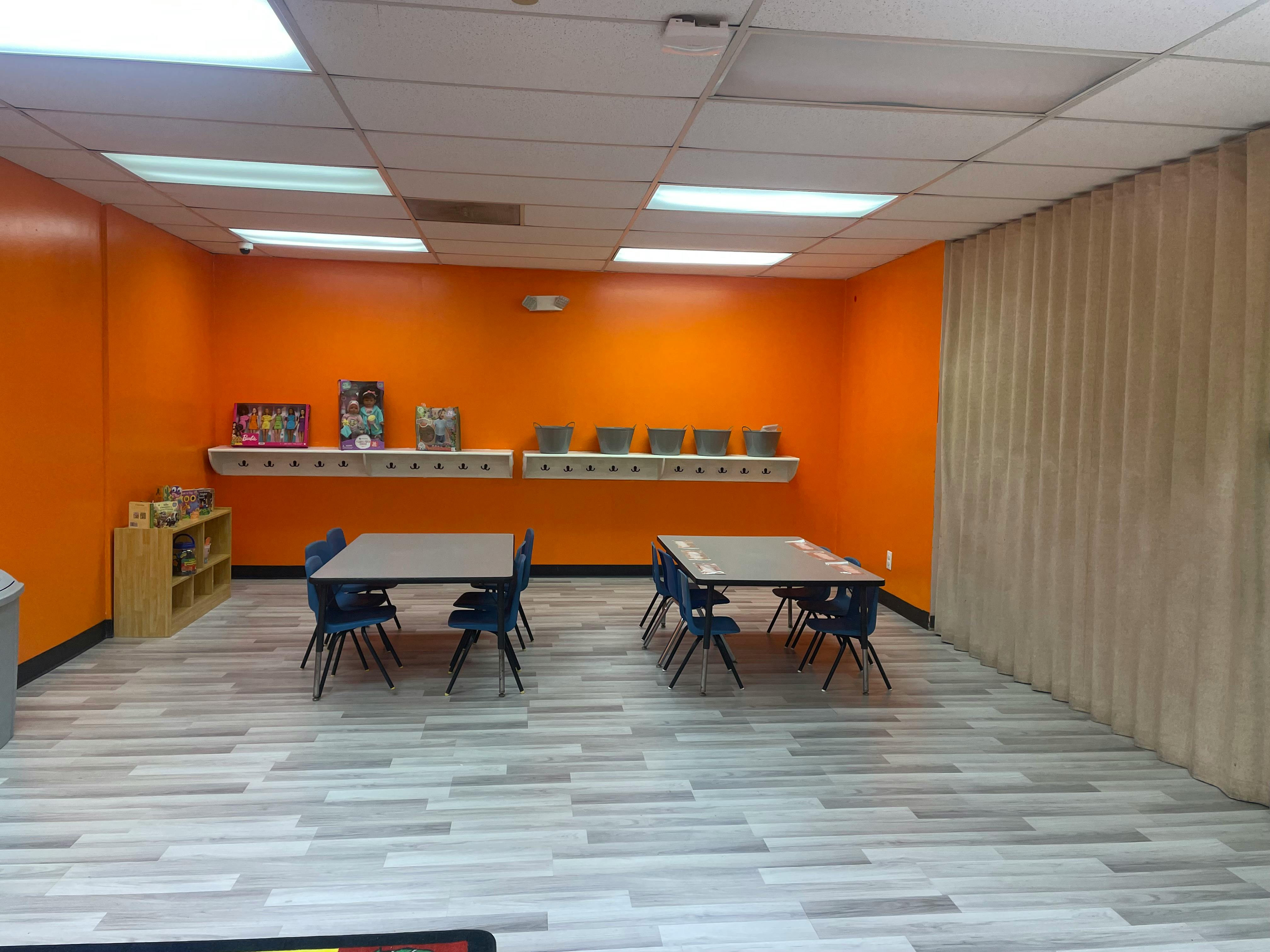 Classroom with orange walls, tables, and chairs
