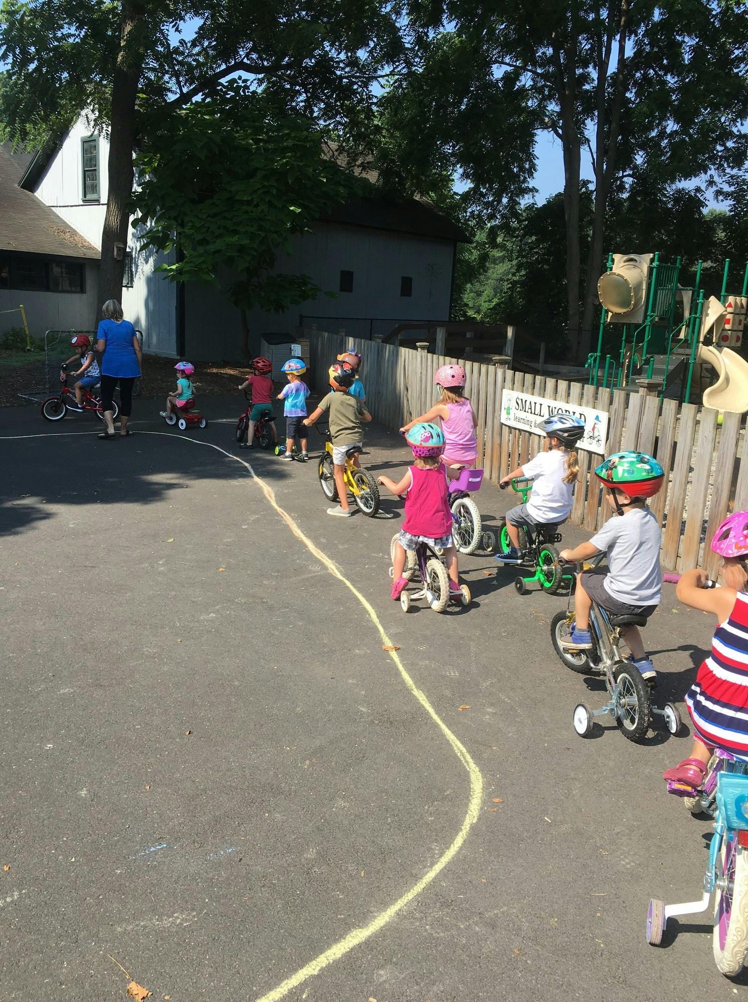 Children on tricycles and bikes with an adult on pavement
