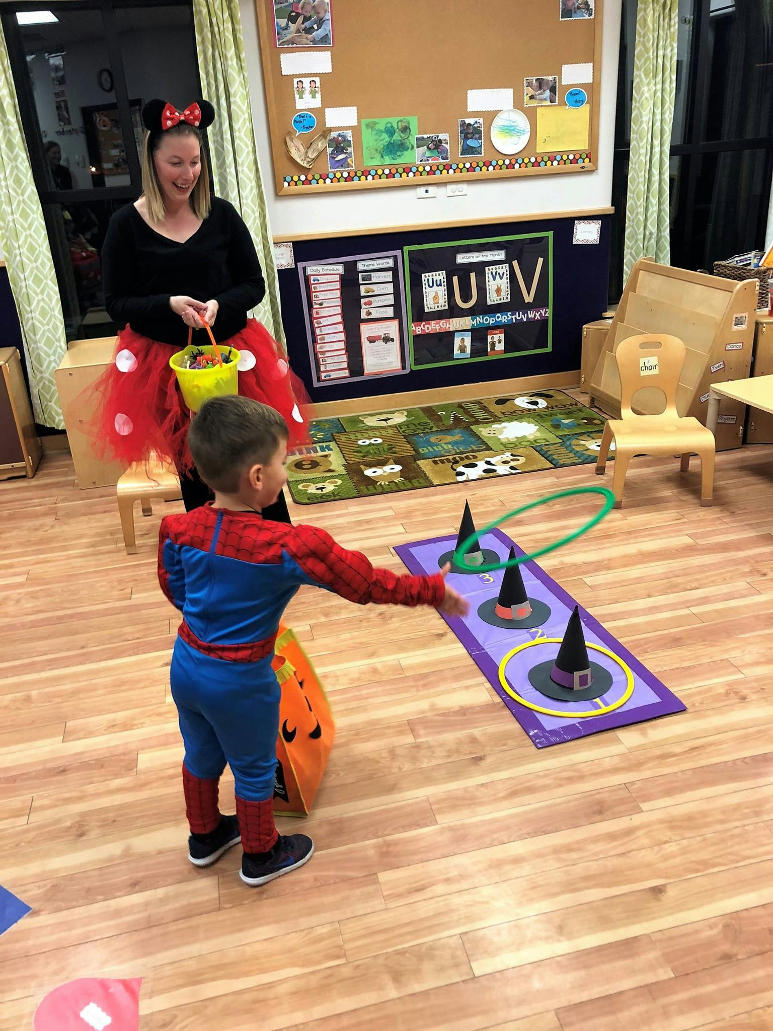 Child in costume playing a ring toss game with a person watching