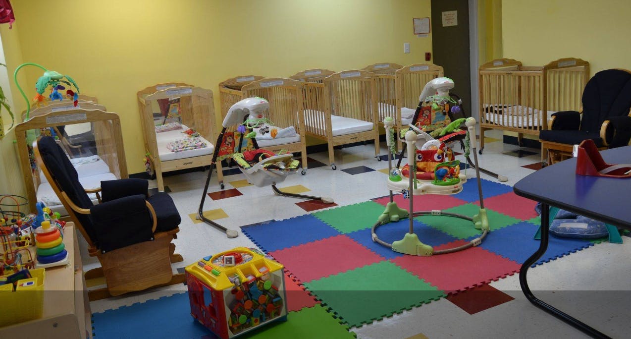 Nursery room with cribs, play mats, and baby bouncers