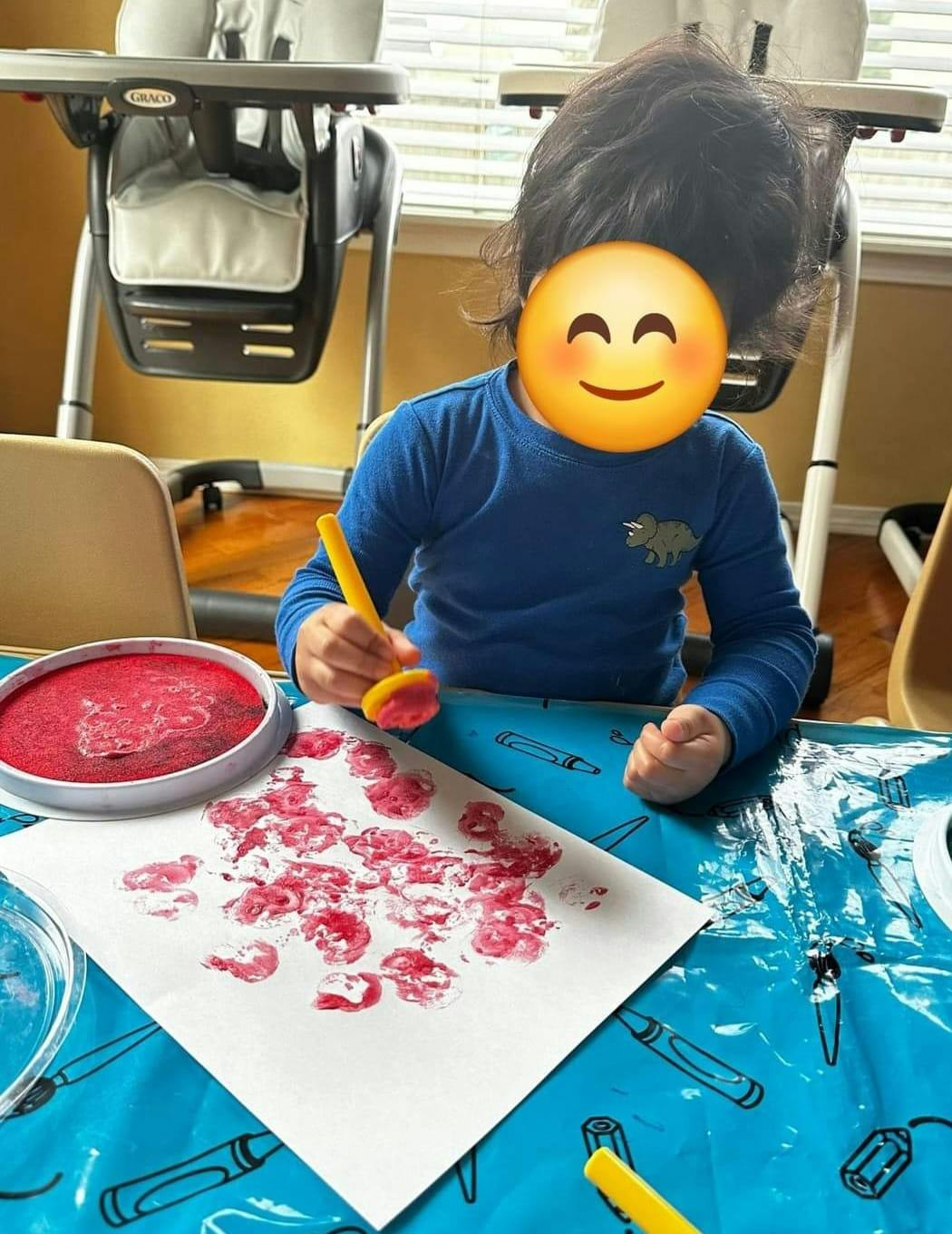 Child making red prints on paper with a stamper