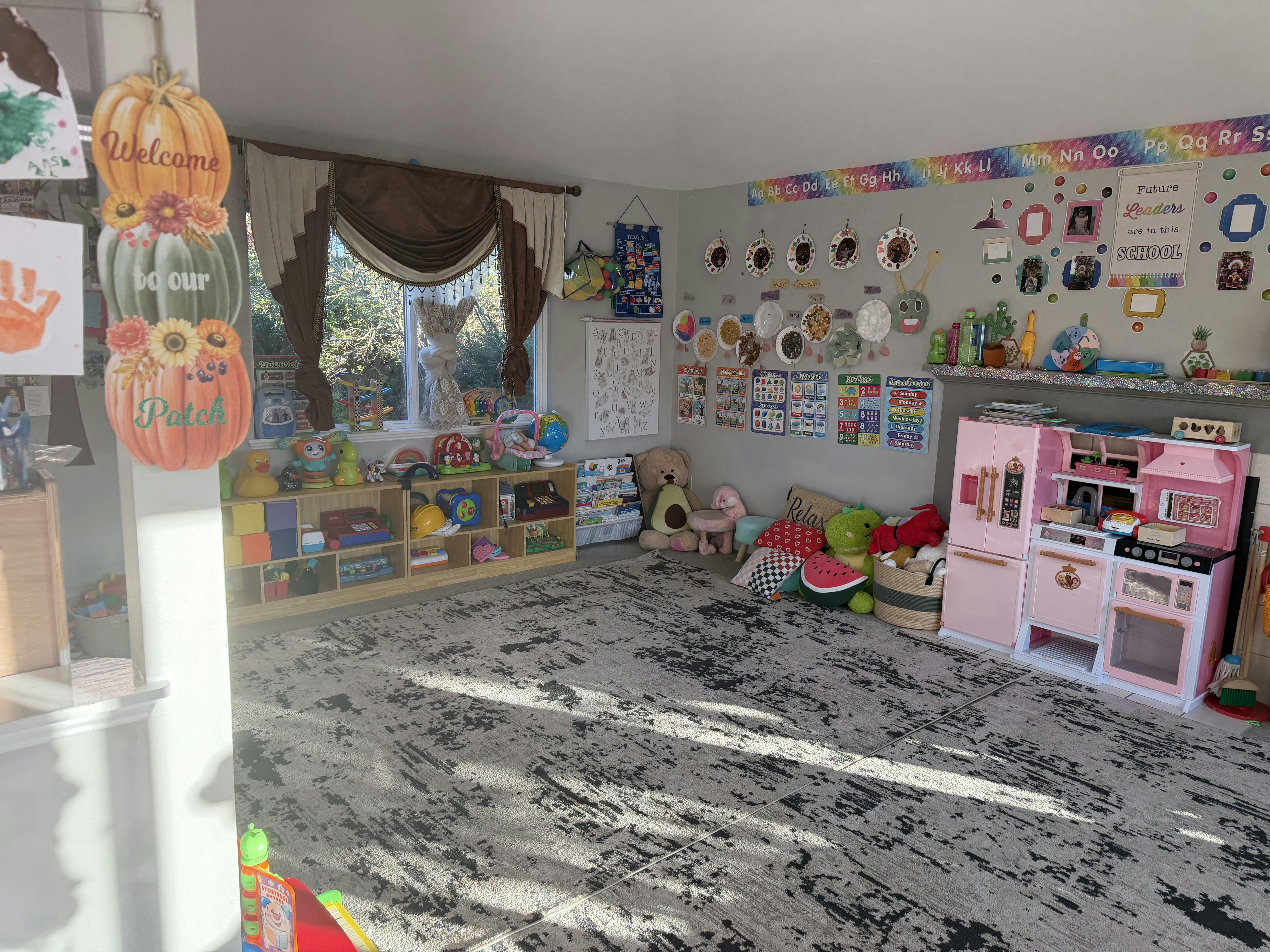 A playroom featuring educational posters, children's toys, and a toy kitchen
