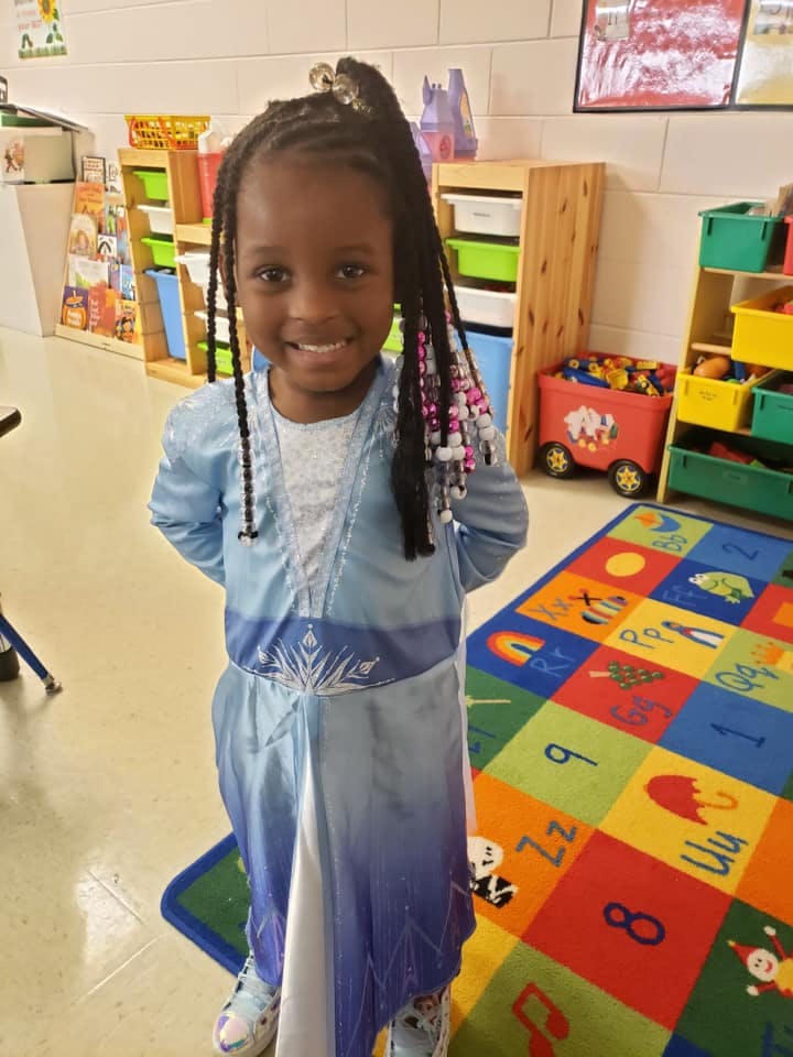Child in a light blue dress standing in a room