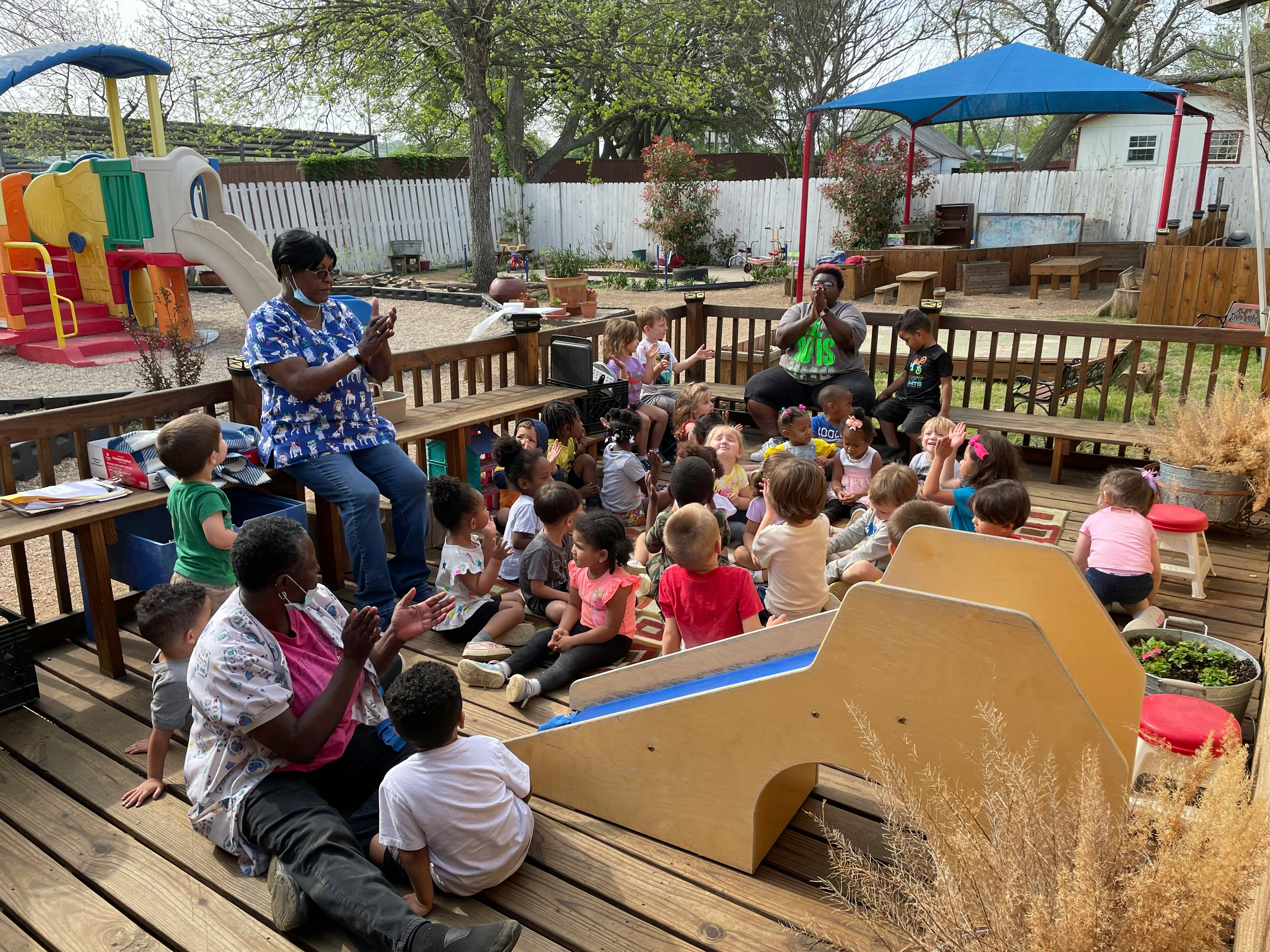 Adults and children gathered on a wooden deck in an outdoor setting