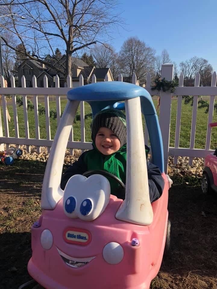 Child in a pink toy car