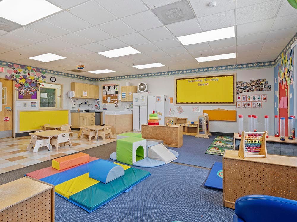 children's classroom with small tables, kitchen area, and soft play equipment