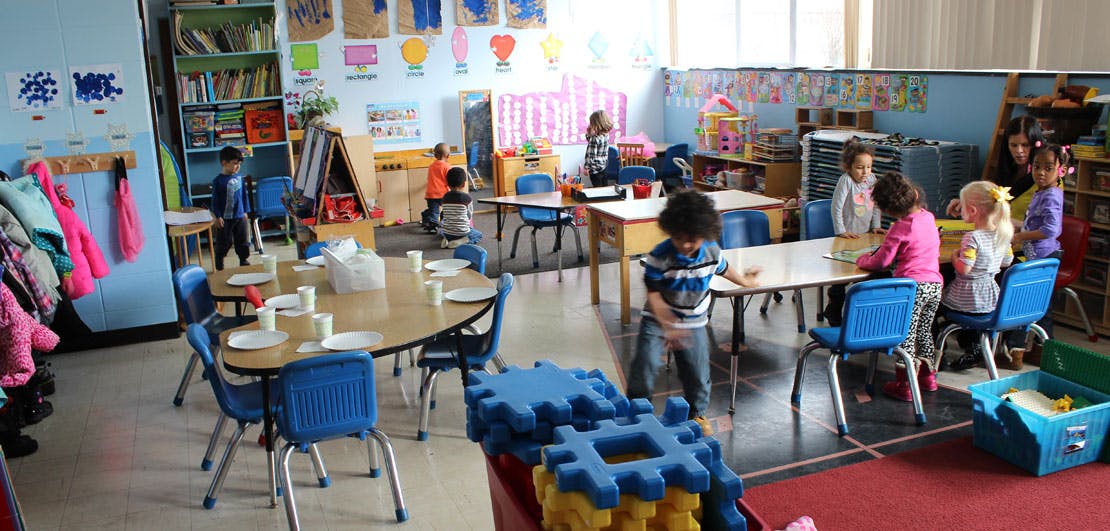 Children in a classroom with tables and chairs