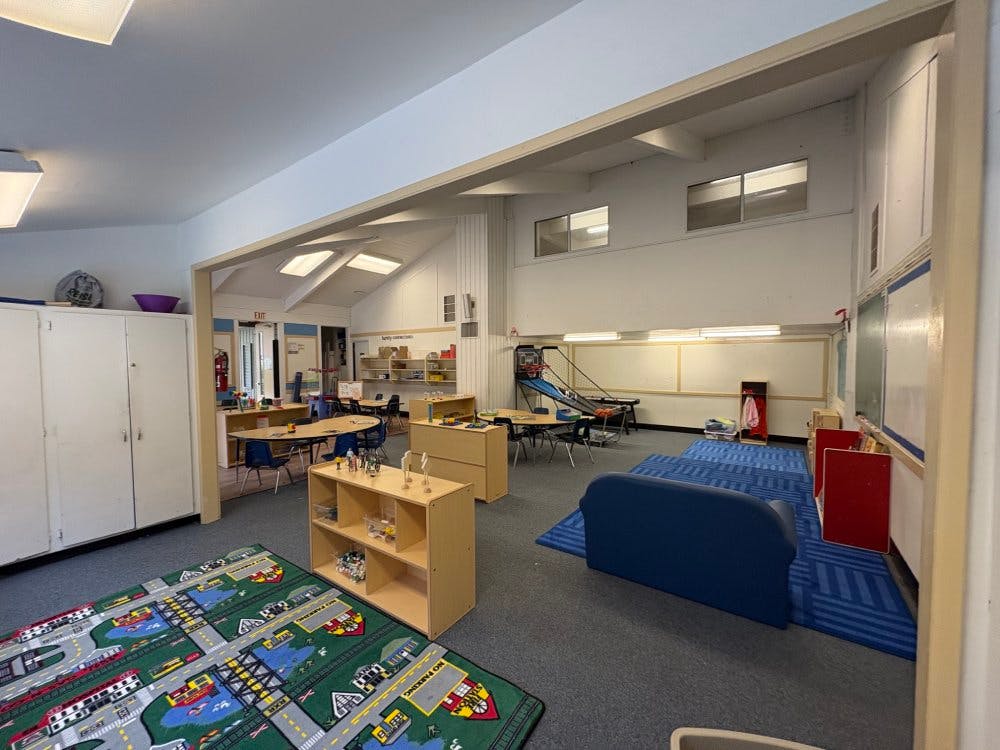 Playroom with small tables and chairs, play mats, and storage units
