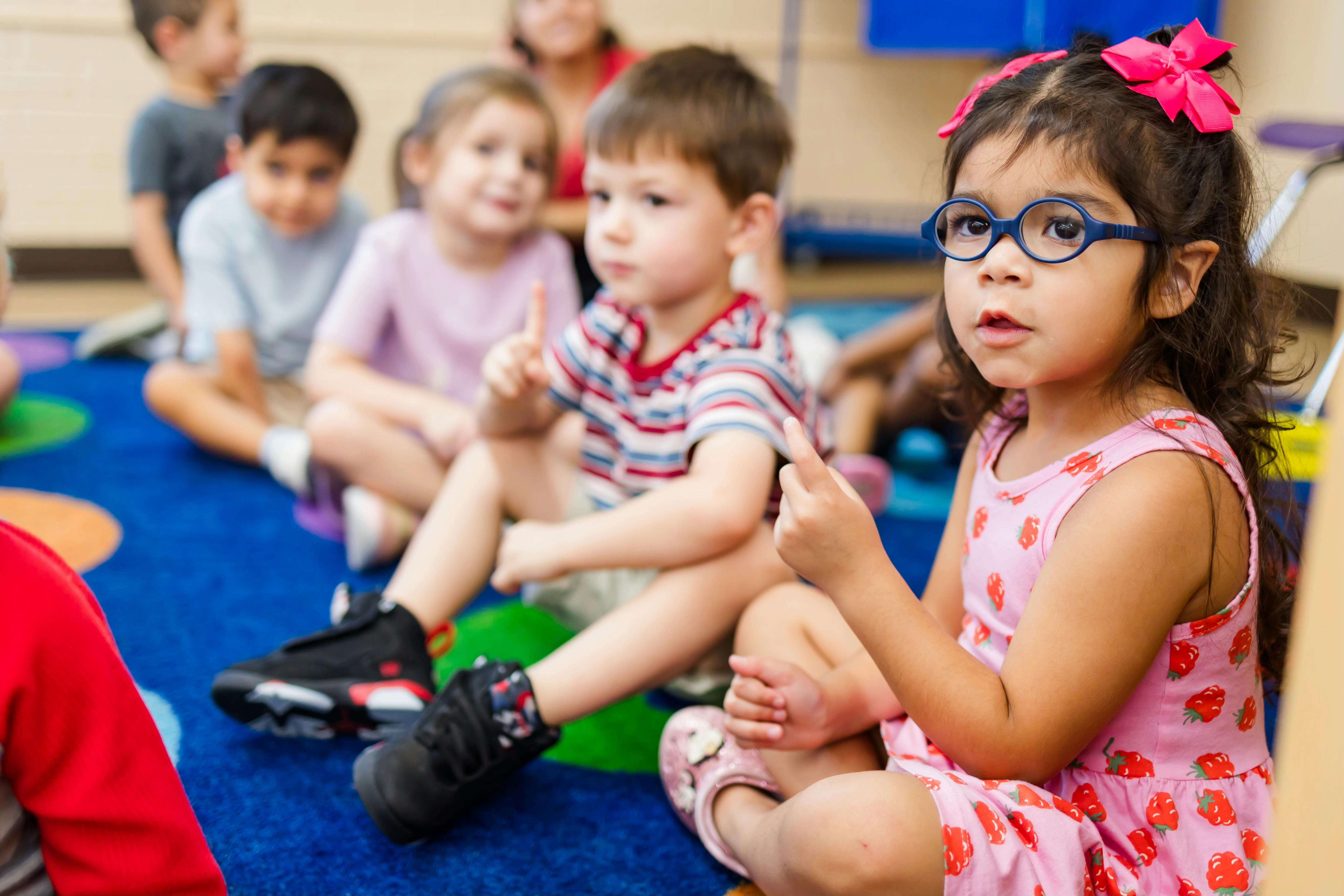 Children sitting on a colorful rug in a classroom