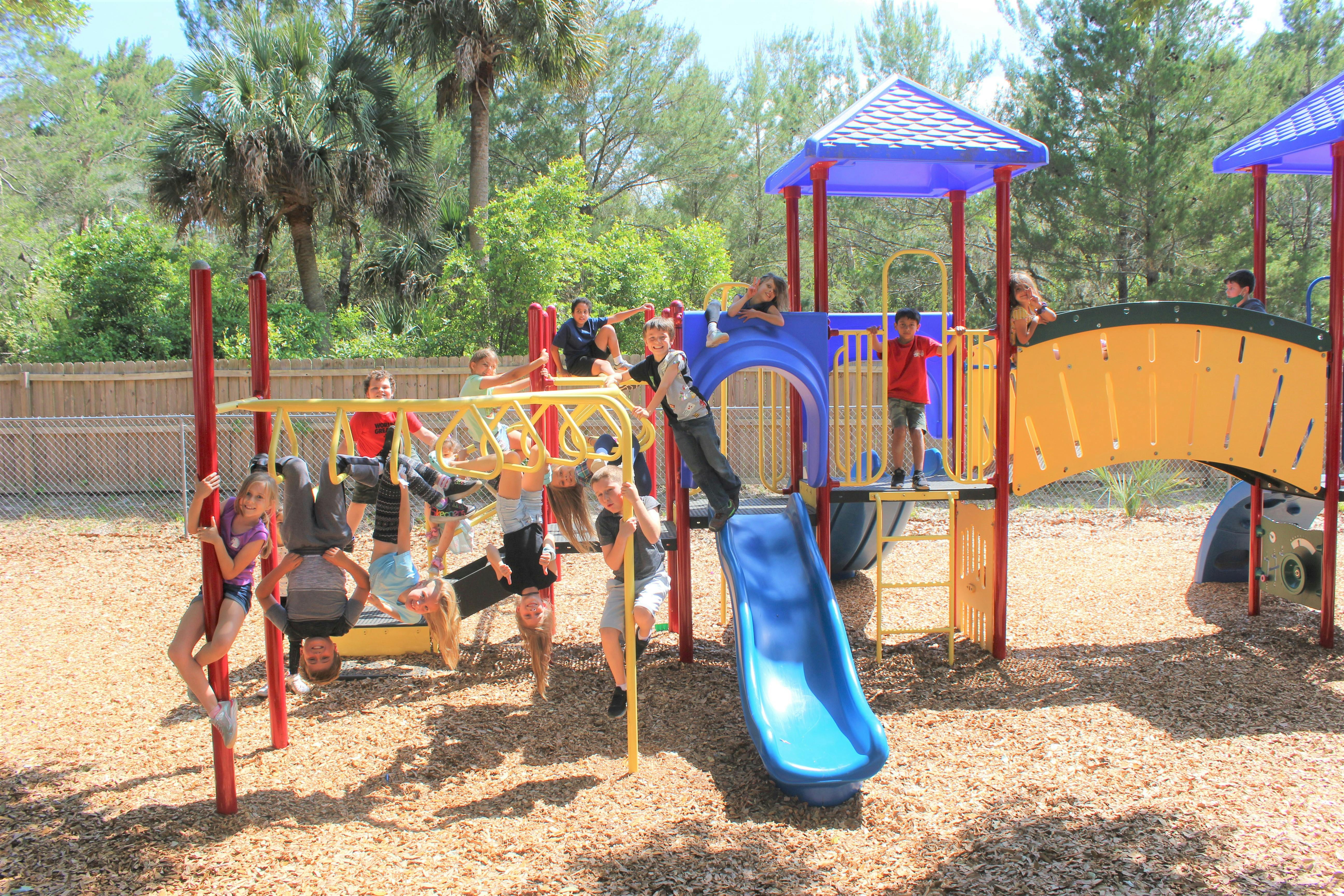Children playing on a playground structure with monkey bars and slides
