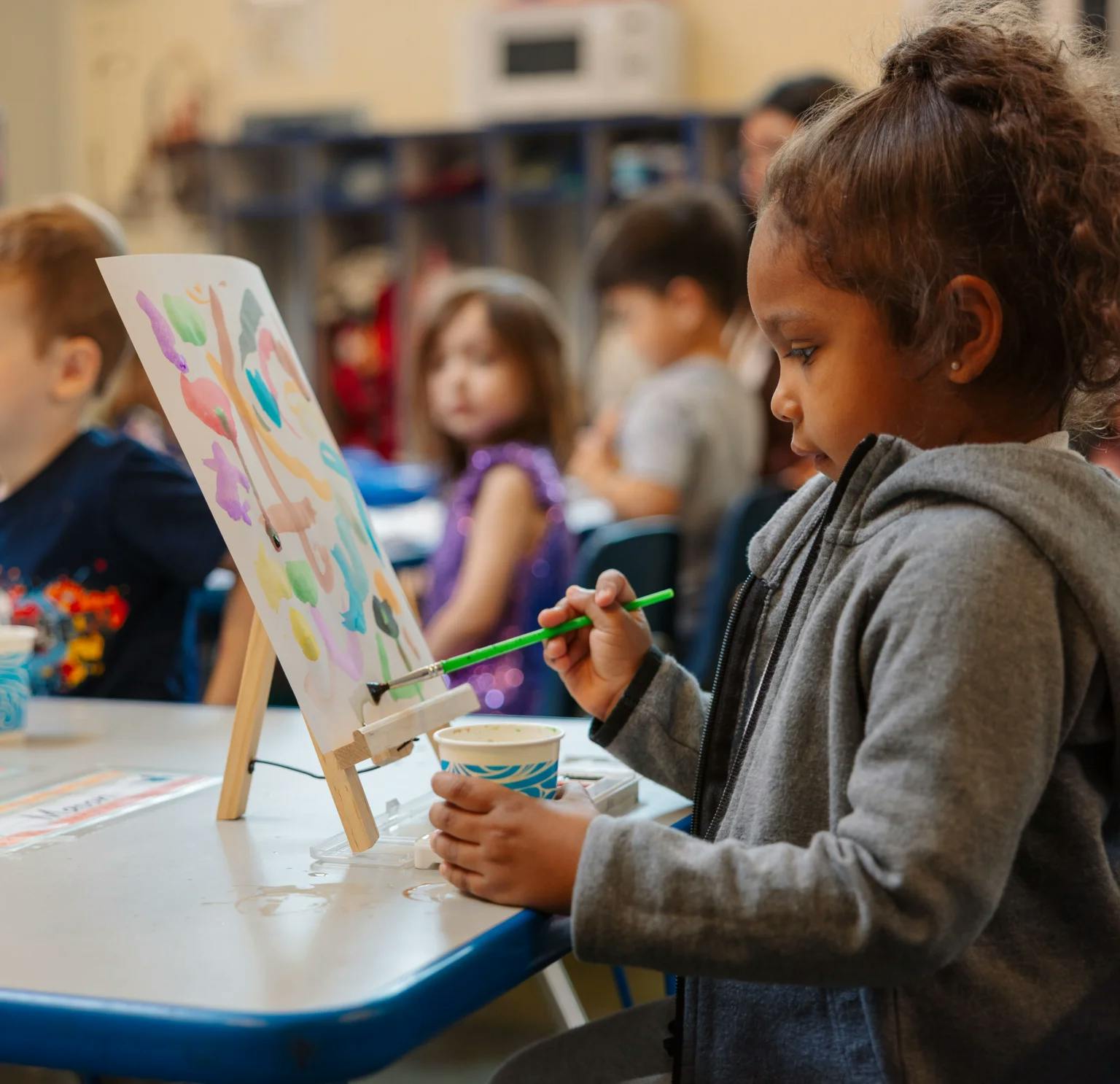 Child painting on an easel in a classroom