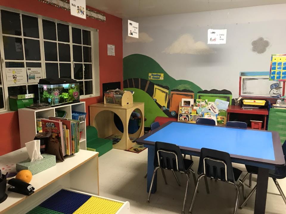 Classroom with a blue table, chairs, and a colorful wall mural