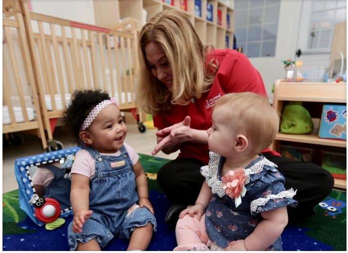 Adult interacting with two babies in a classroom