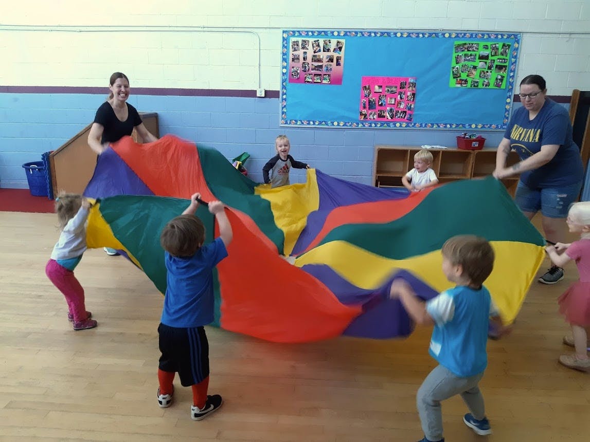 Adults and children playing with a colorful parachute