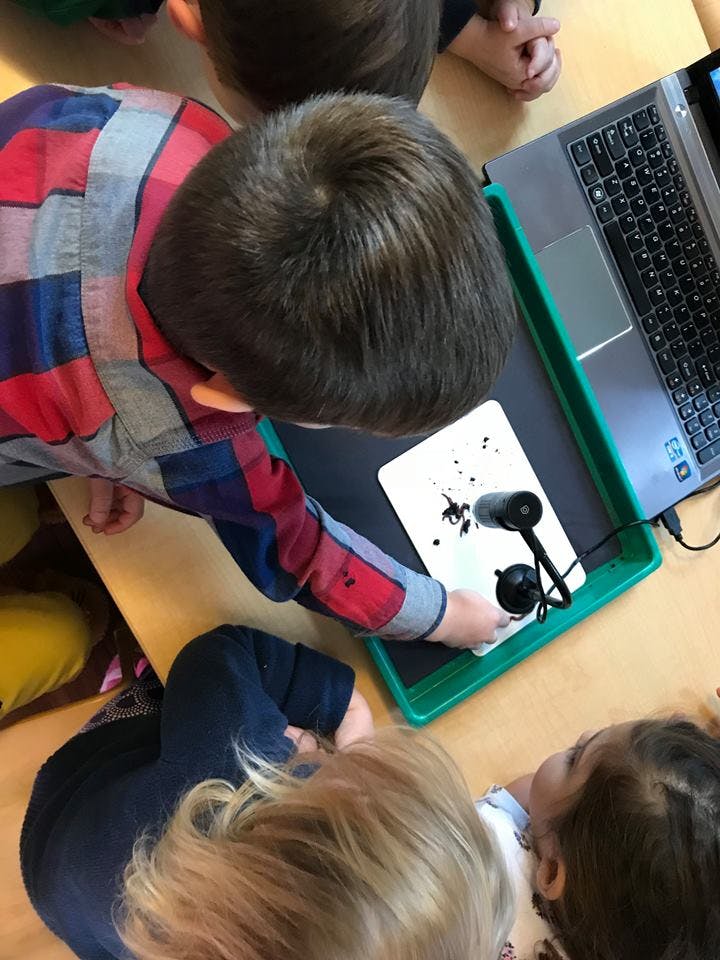 Child using a microscope connected to a laptop