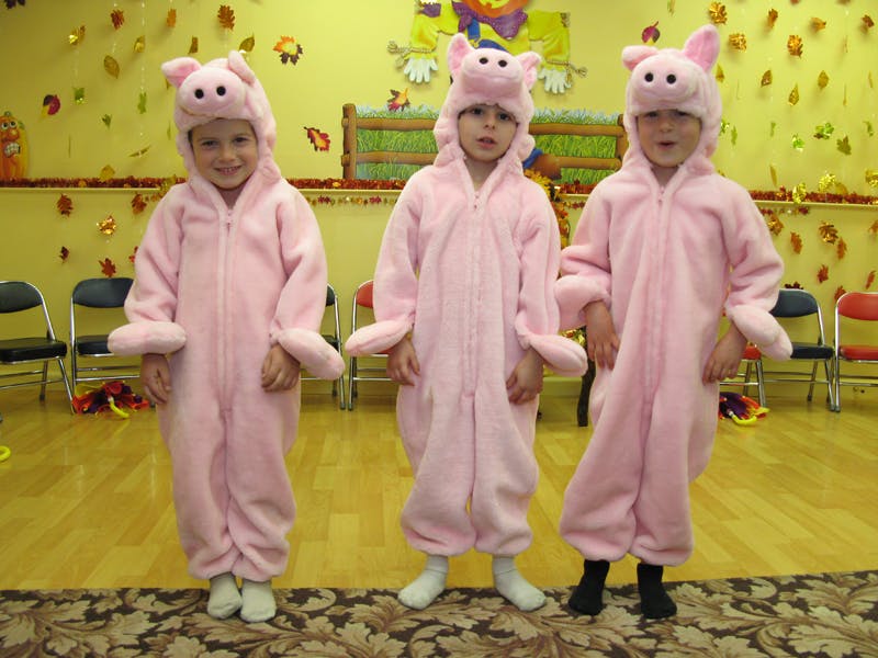 Three children in pink pig costumes standing together