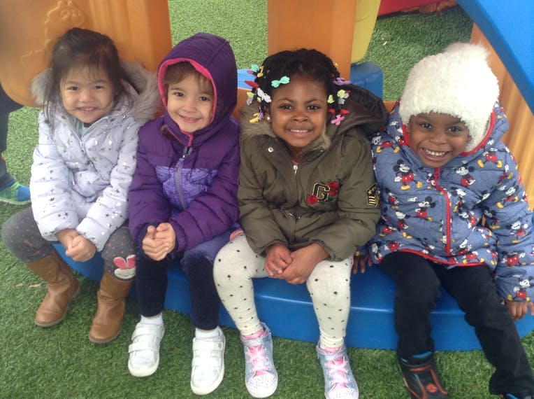 Four children sitting together on a blue bench