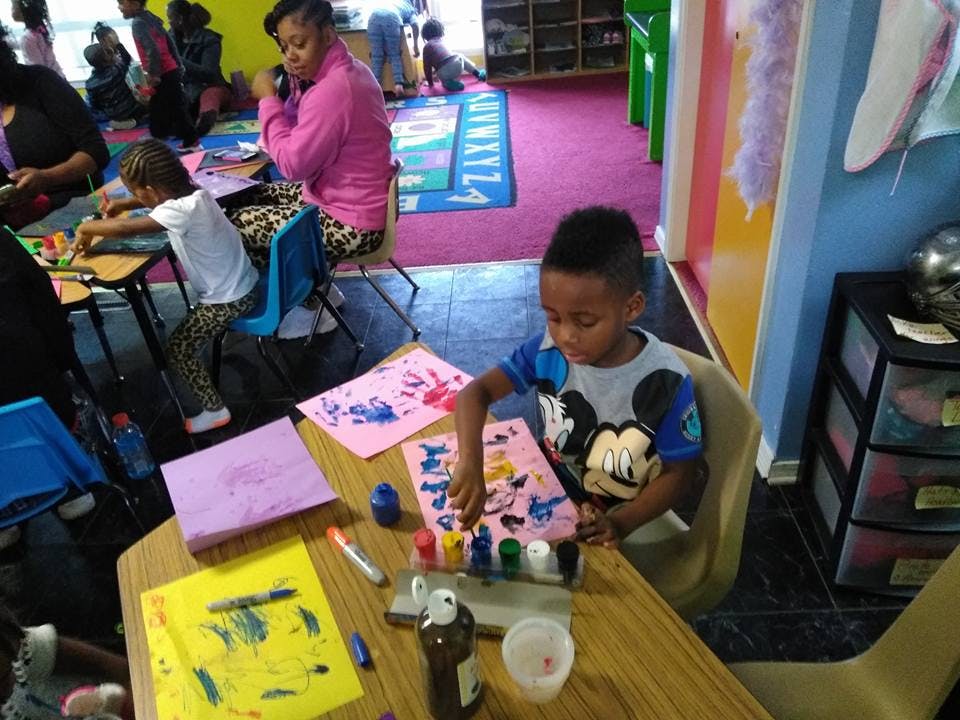 Child painting at a table in a classroom