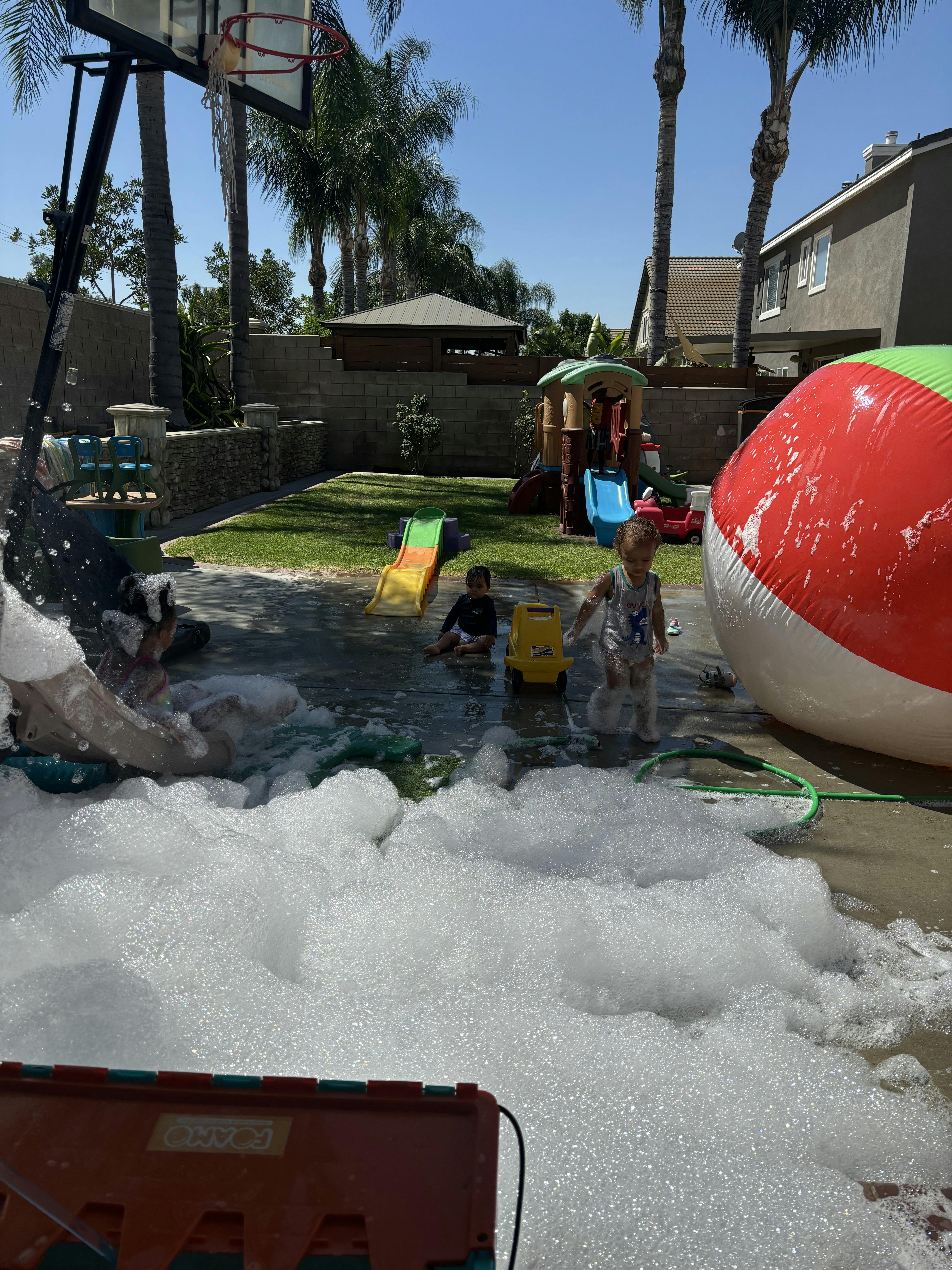 Children playing in bubbles on a patio with a large beach ball