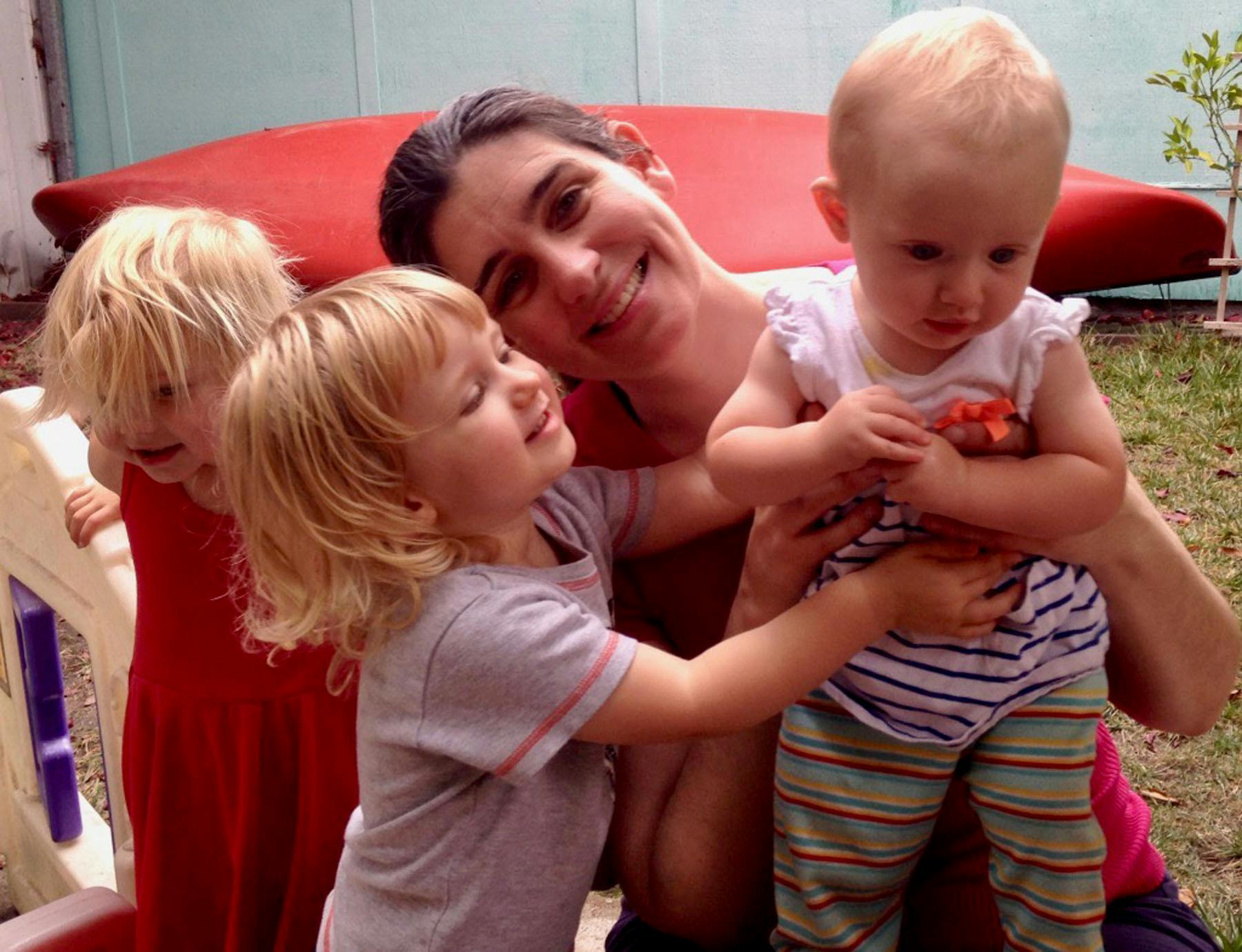 Person holding a child, with two other children nearby