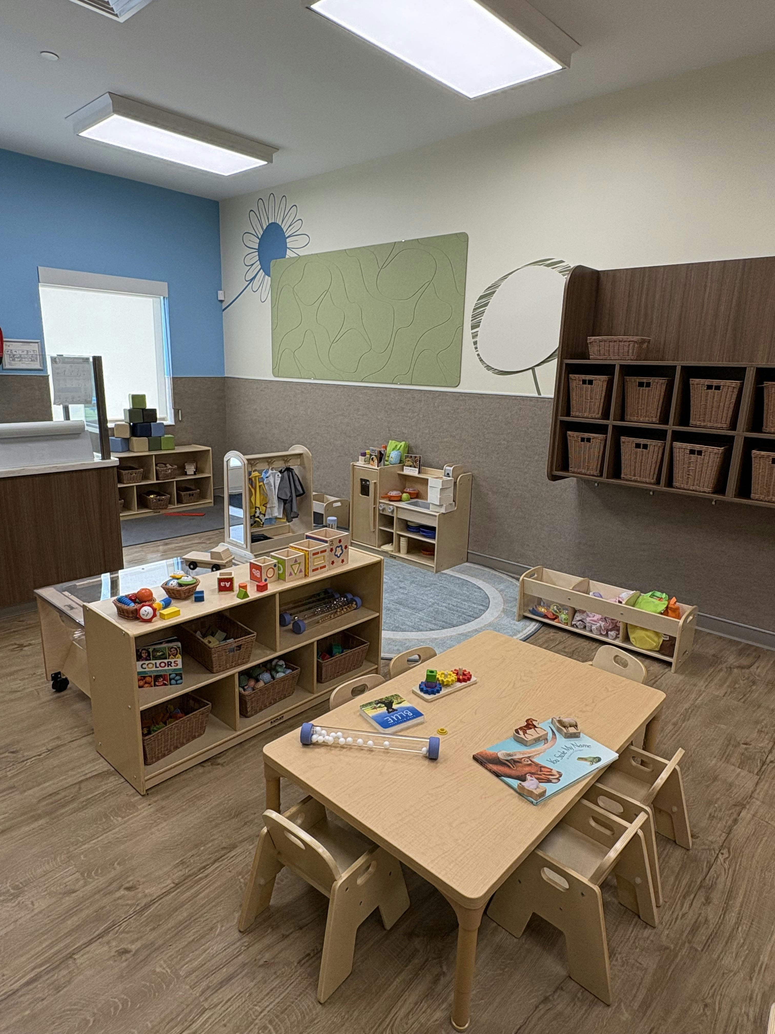 Classroom with small tables, chairs, and shelves with toys