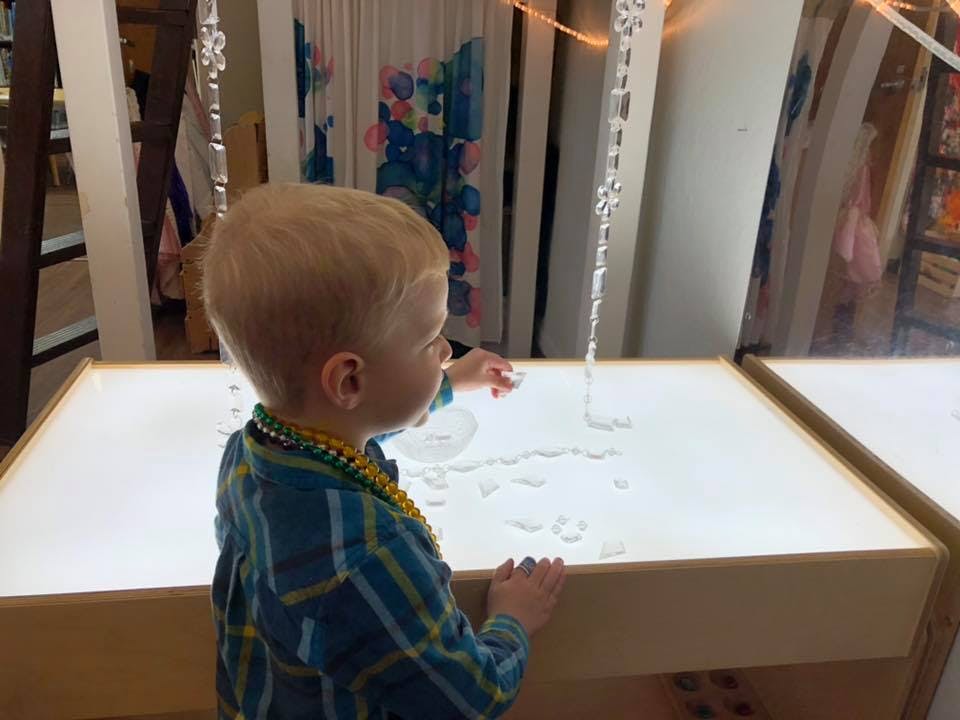 Child playing with clear objects on a light table