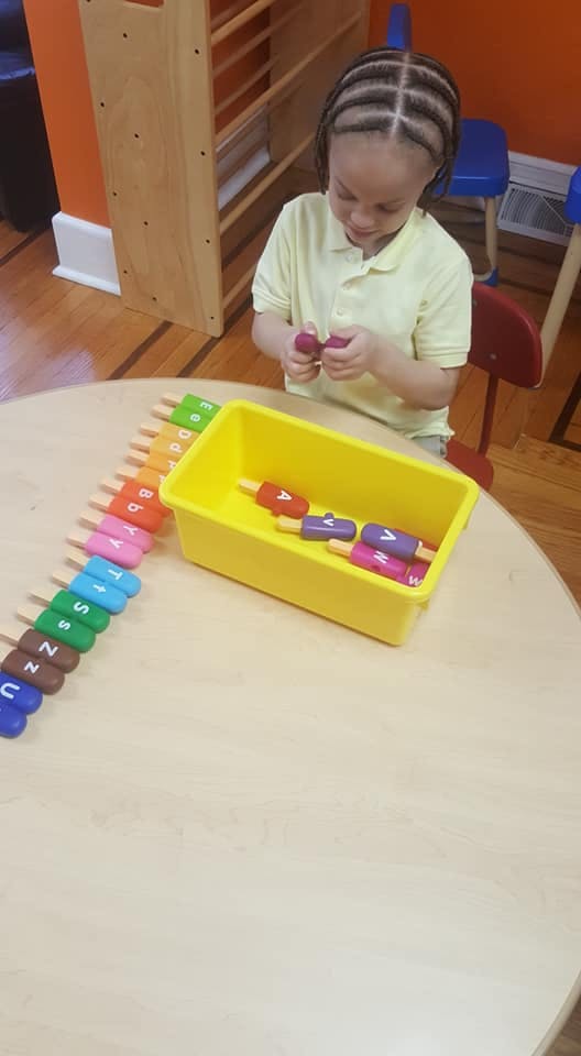 Child playing with letter-matching popsicles at a table