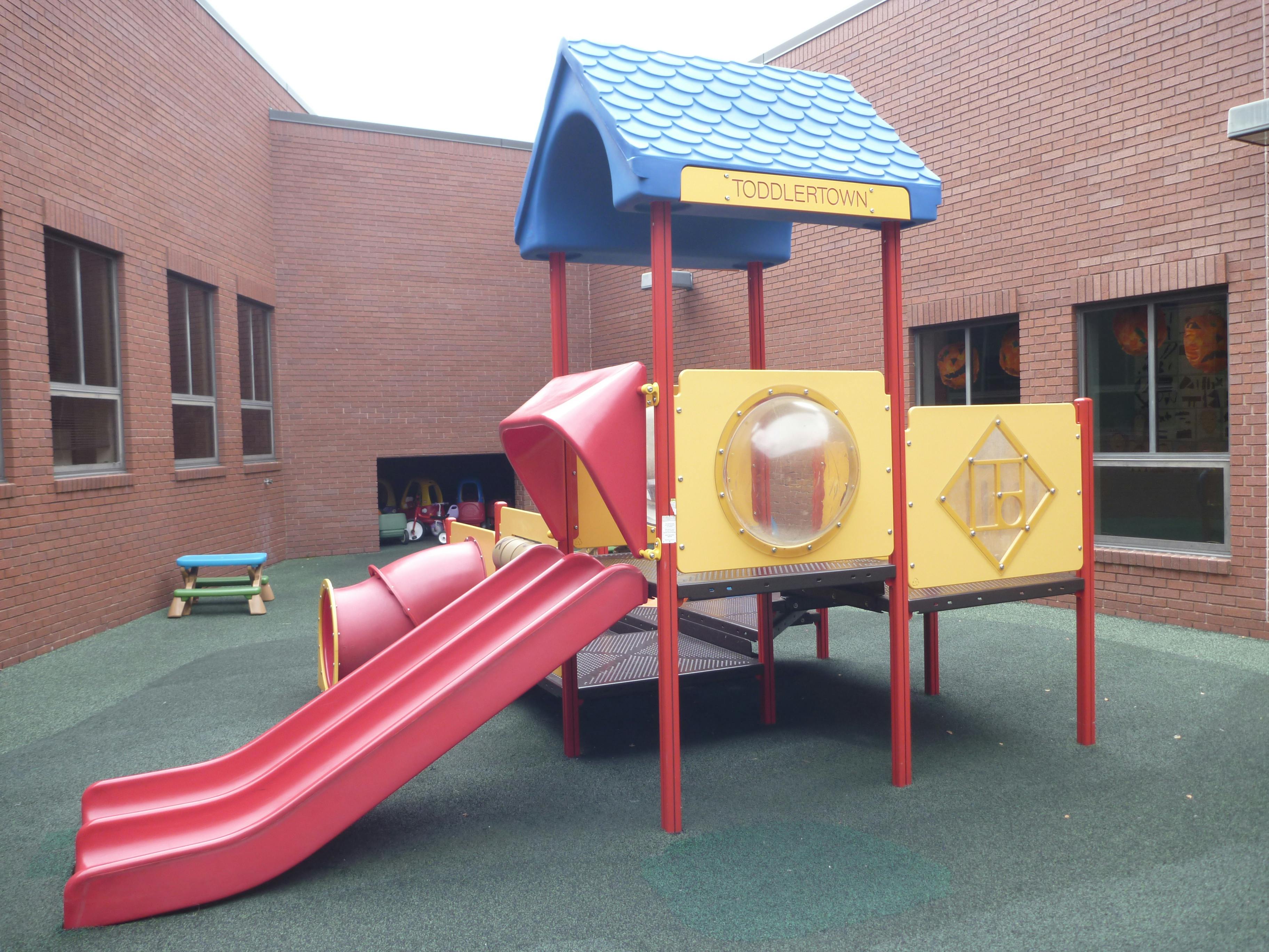 Playground structure with red slide and blue roof