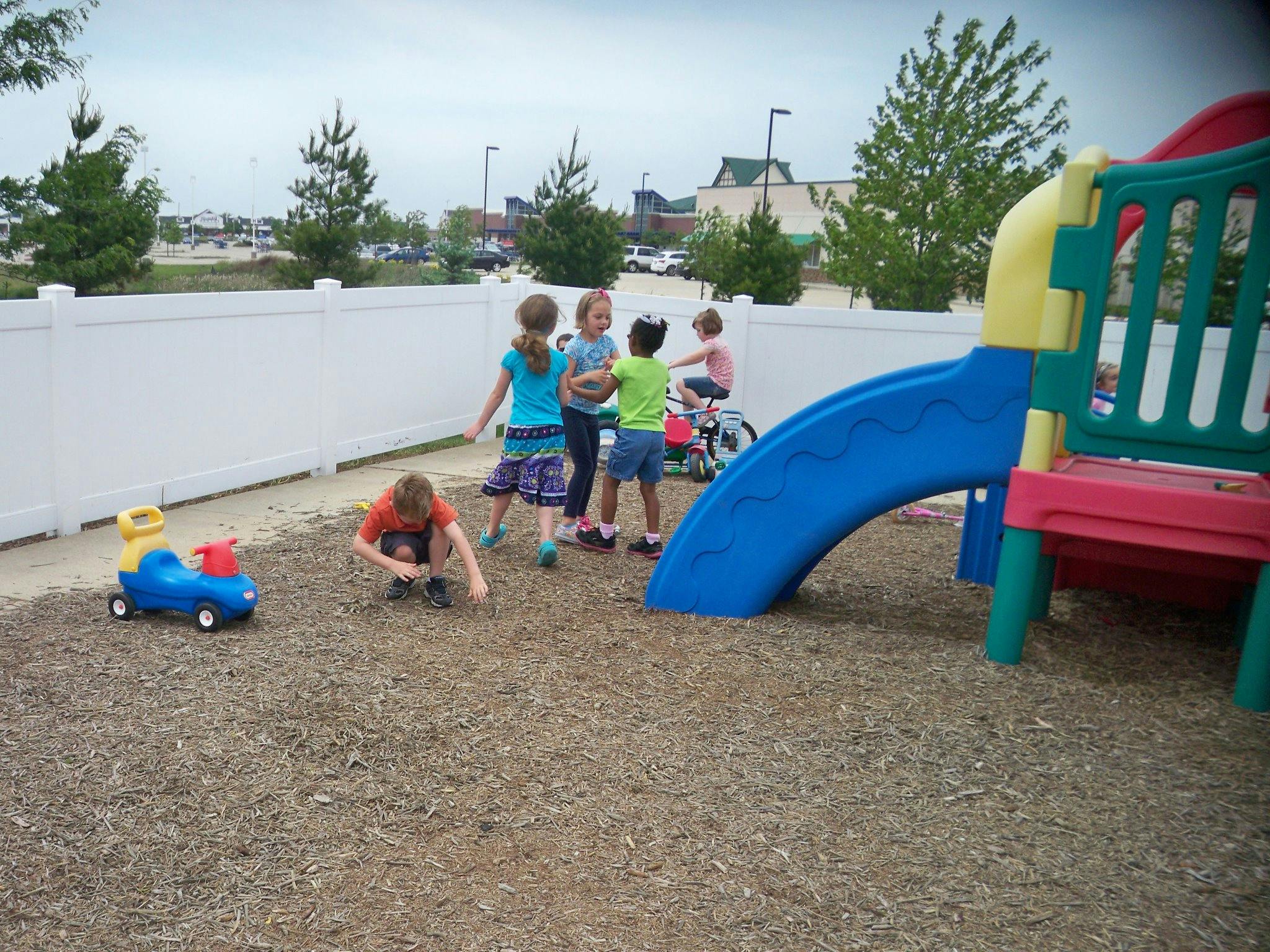 Children playing on a playground with a slide and wood chips