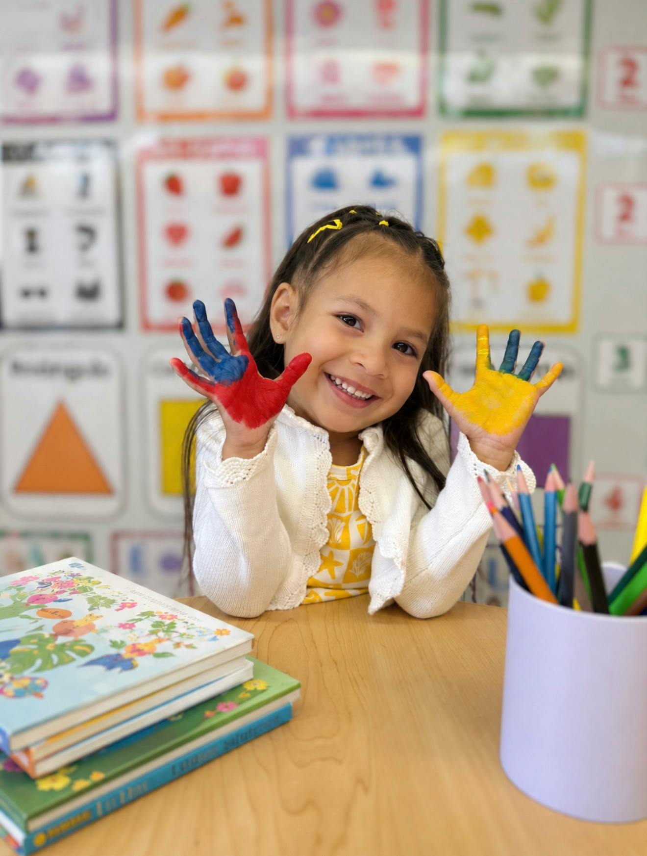 Child with paint on hands in a classroom