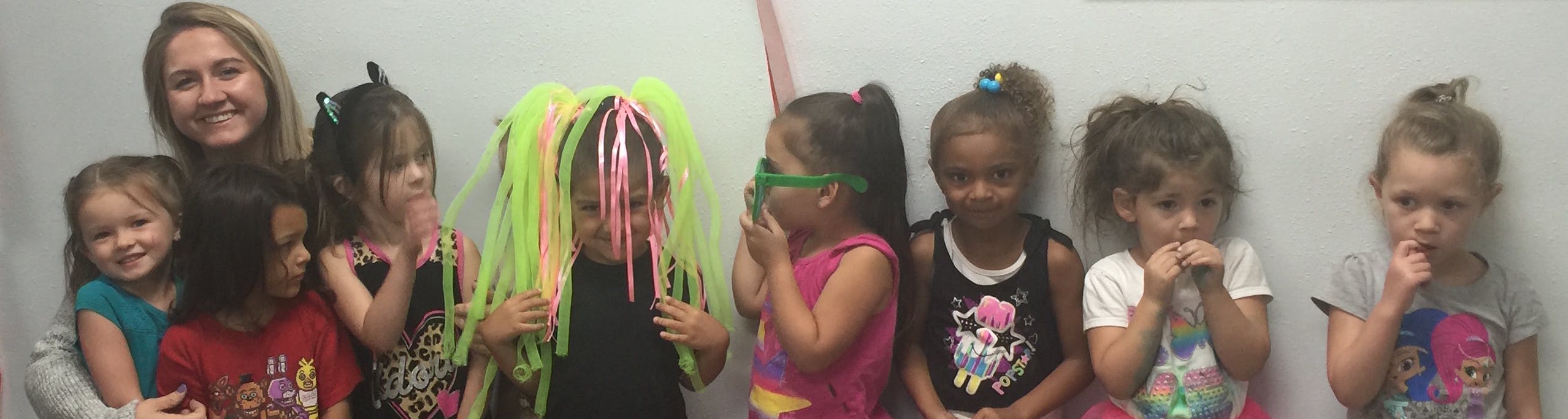 Adult and multiple children posing, one child wearing a neon wig